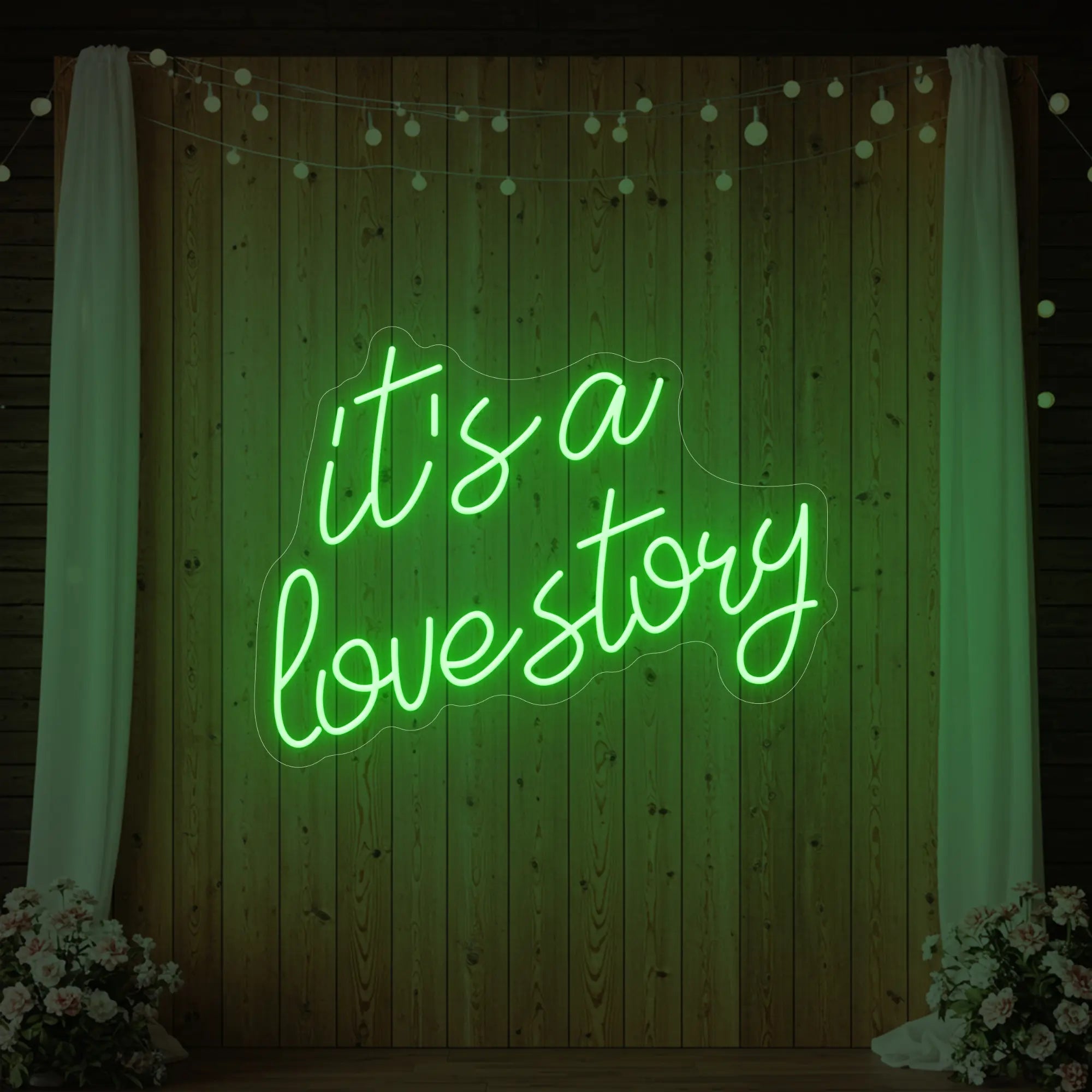 Photo of the 'It’s a Love Story' neon sign glowing in green against a styled interior wall.
