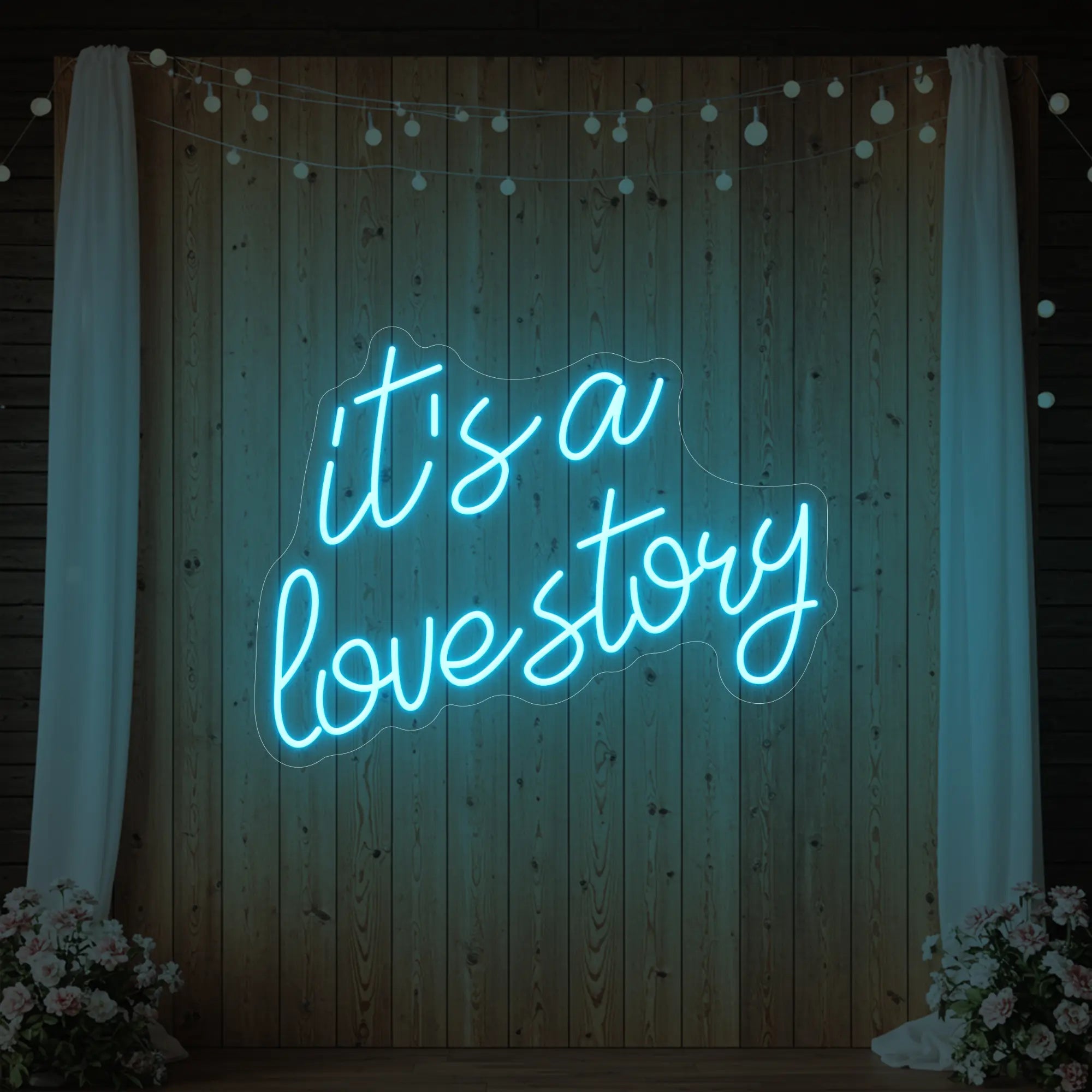 Photo of the 'It’s a Love Story' neon sign glowing in ice blue against a styled interior wall.