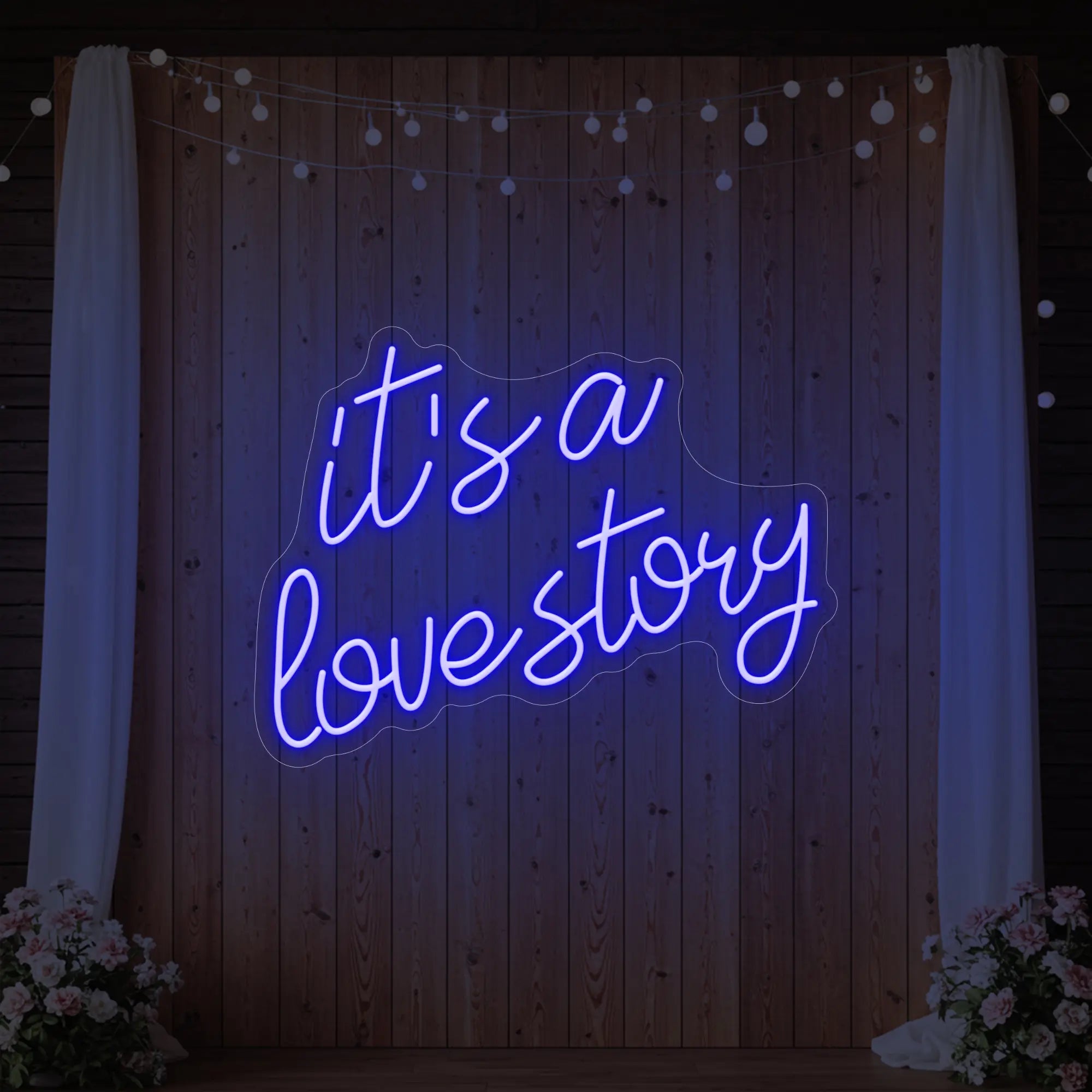 Photo of the 'It’s a Love Story' neon sign glowing in deep blue against a styled interior wall.