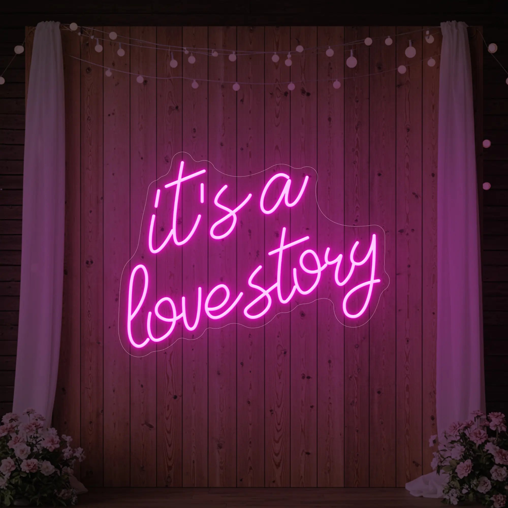 Photo of the 'It’s a Love Story' neon sign glowing in light pink against a styled interior wall.