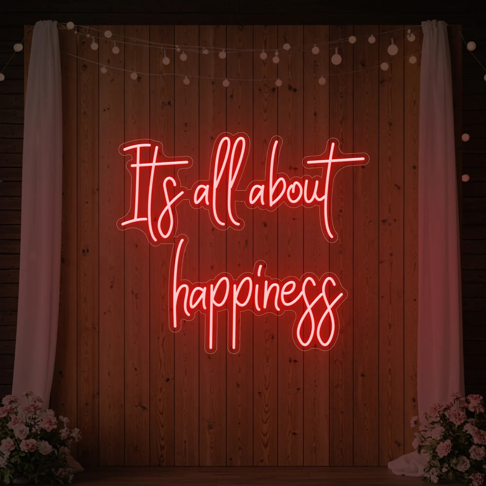 Photo of the 'It’s All About Happiness' neon sign glowing in red against a styled interior wall.