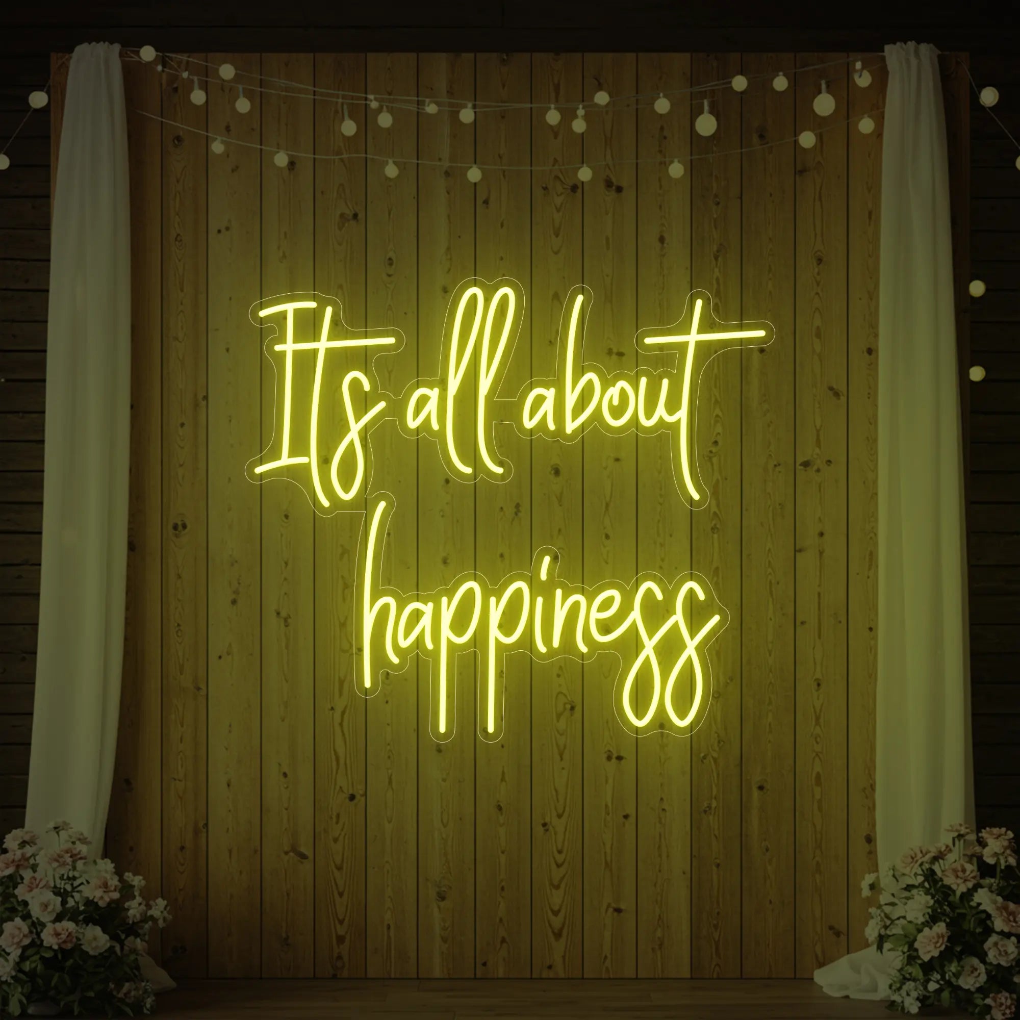 Photo of the 'It’s All About Happiness' neon sign glowing in lemon yellow against a styled interior wall.