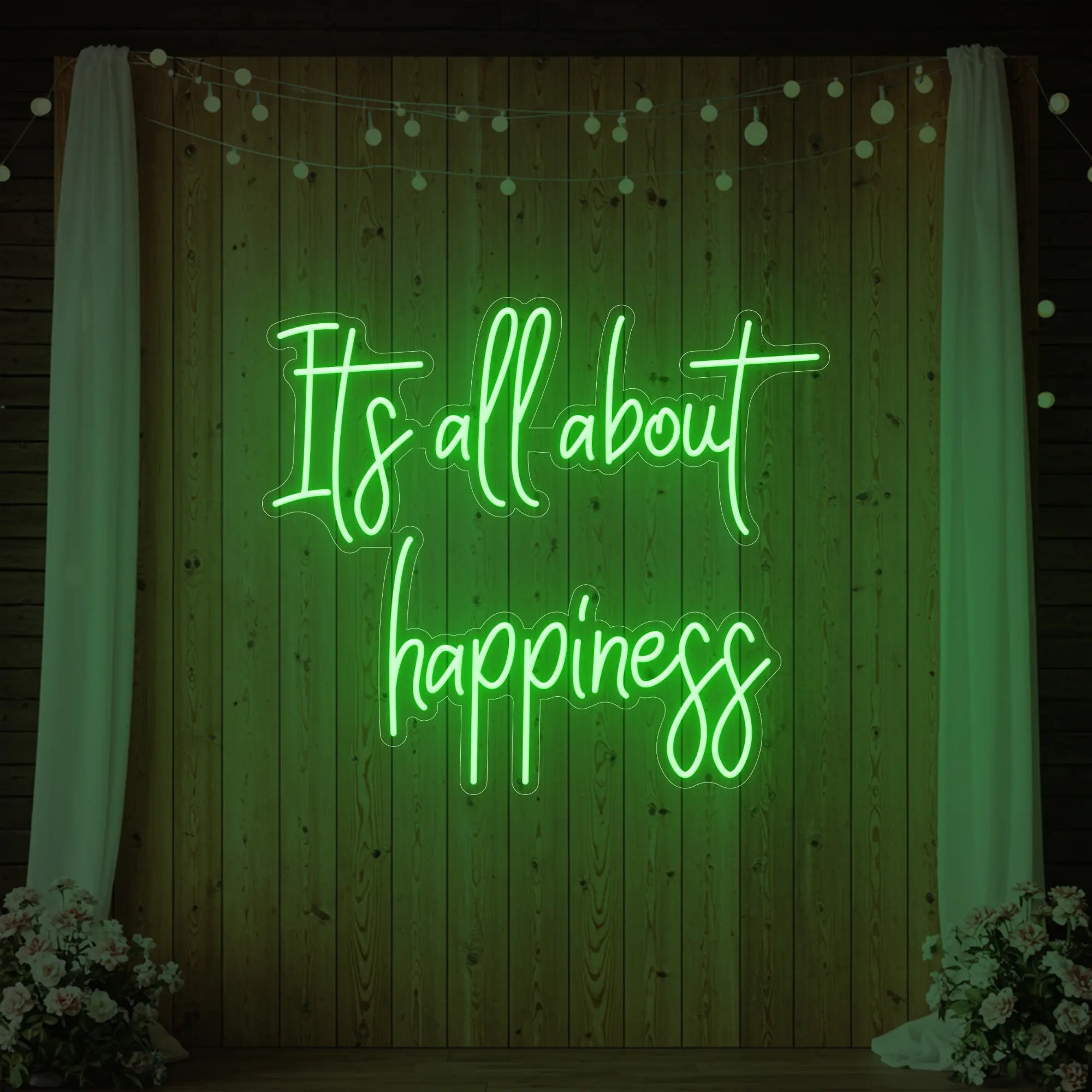 Photo of the 'It’s All About Happiness' neon sign glowing in green against a styled interior wall.