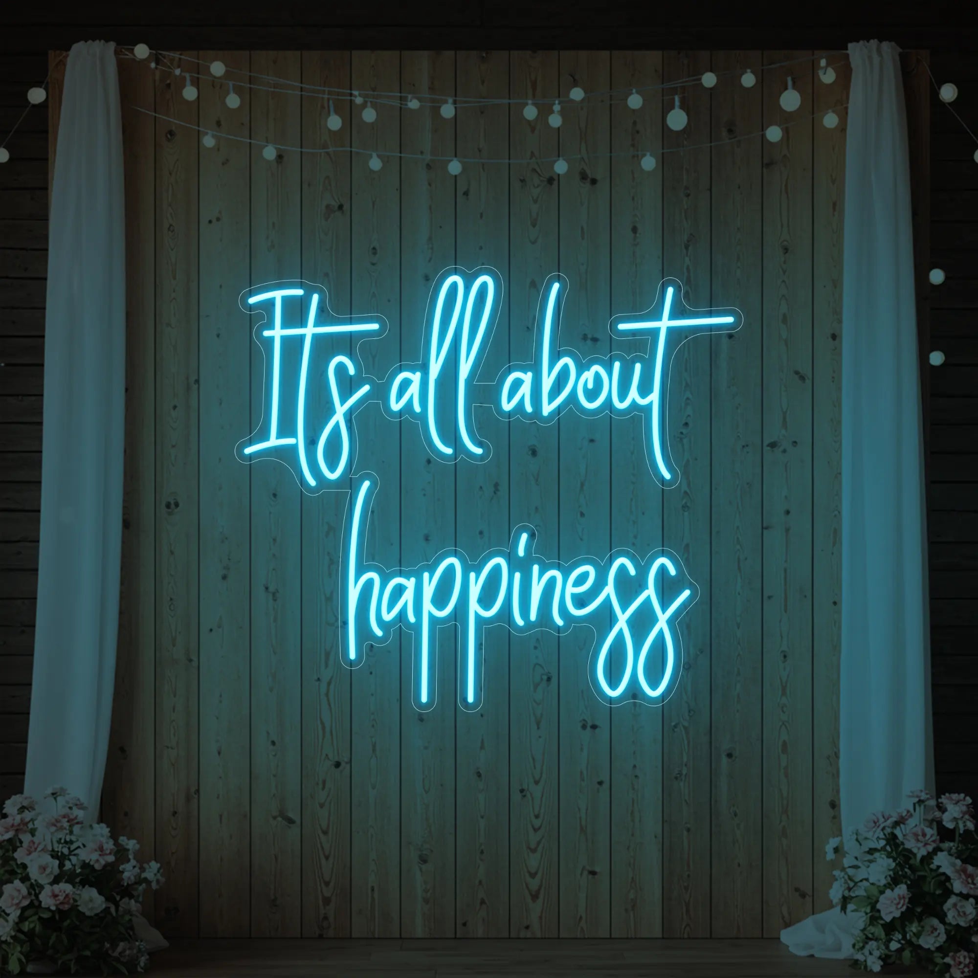 Photo of the 'It’s All About Happiness' neon sign glowing in ice blue against a styled interior wall.