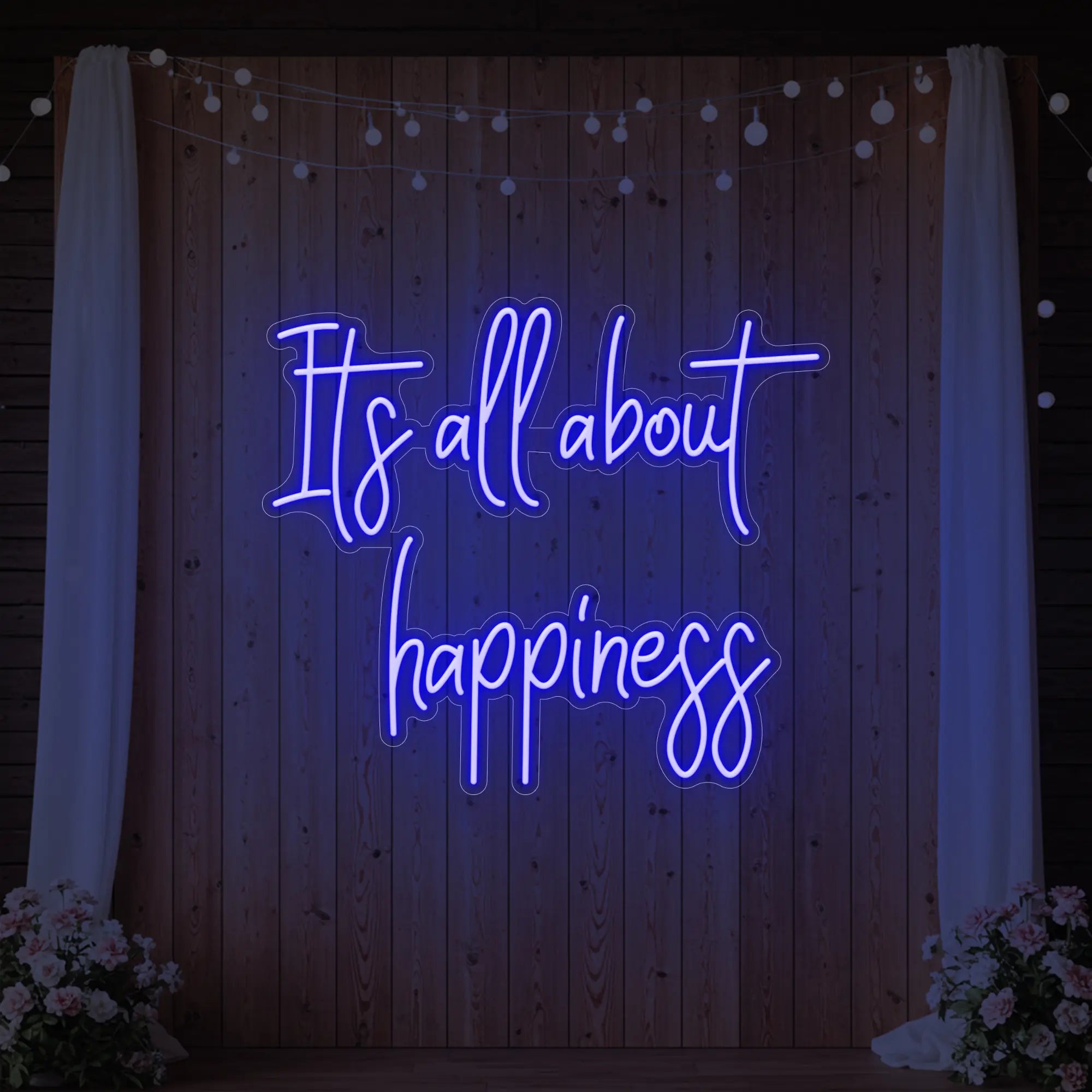 Photo of the 'It’s All About Happiness' neon sign glowing in deep blue against a styled interior wall.