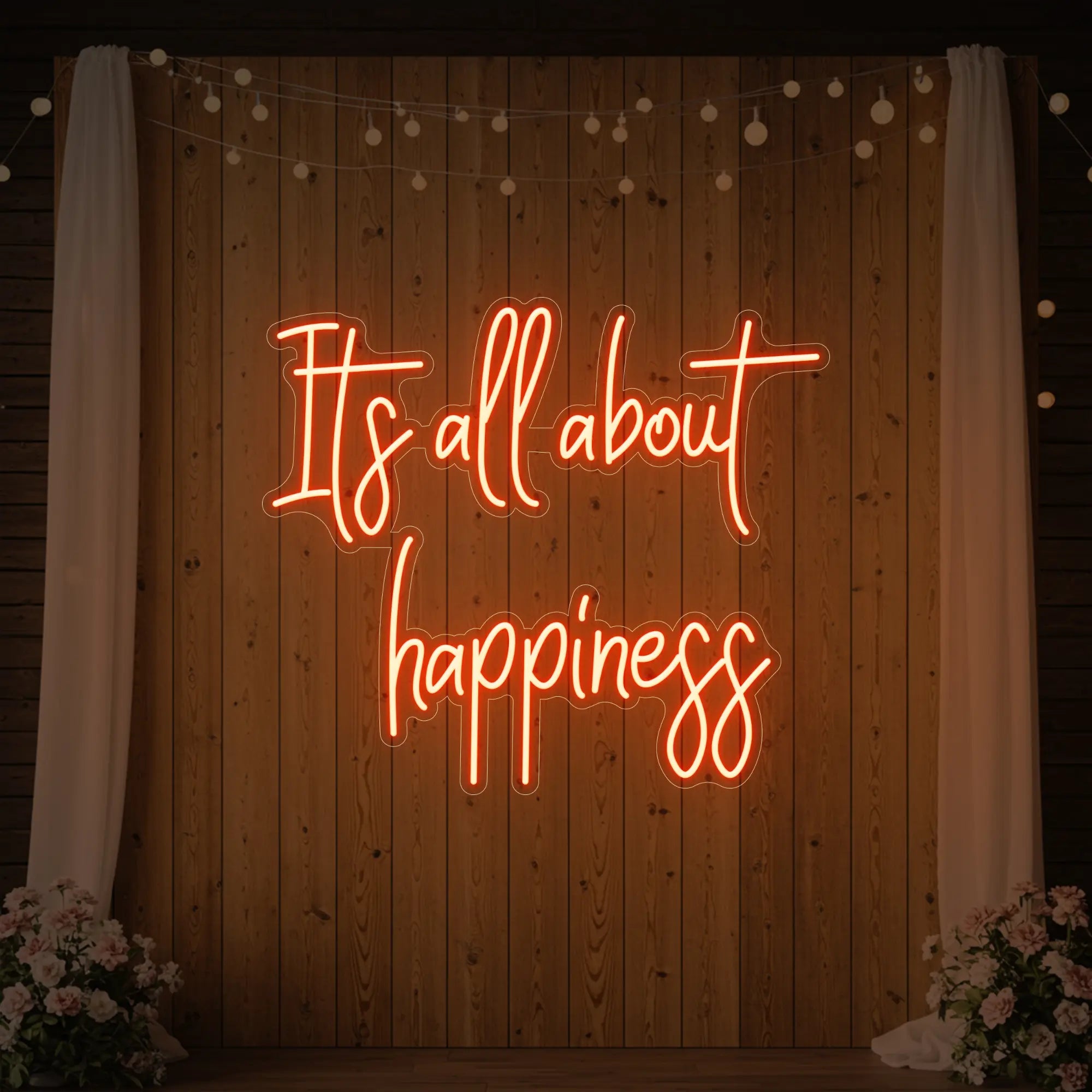 Photo of the 'It’s All About Happiness' neon sign glowing in golden yellow against a styled interior wall.