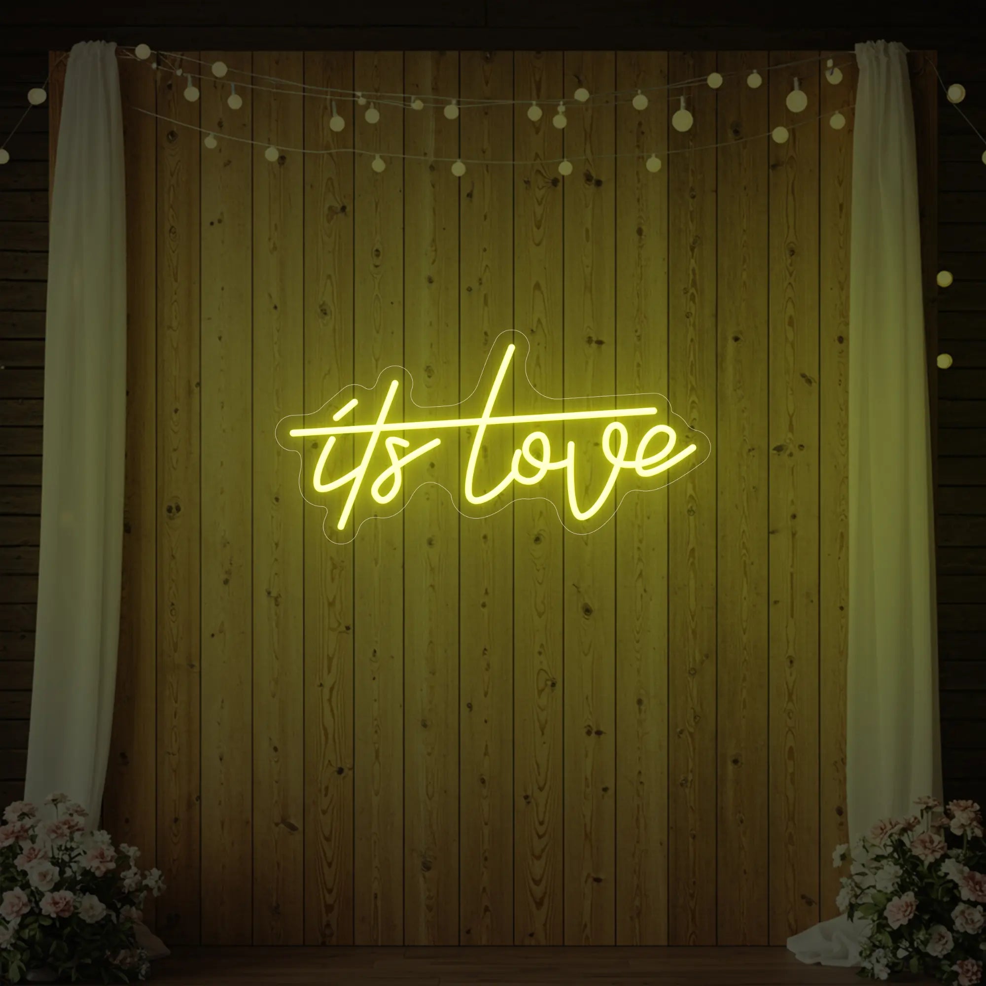 Photo of the 'It’s Love' neon sign glowing in lemon yellow against a styled interior wall.