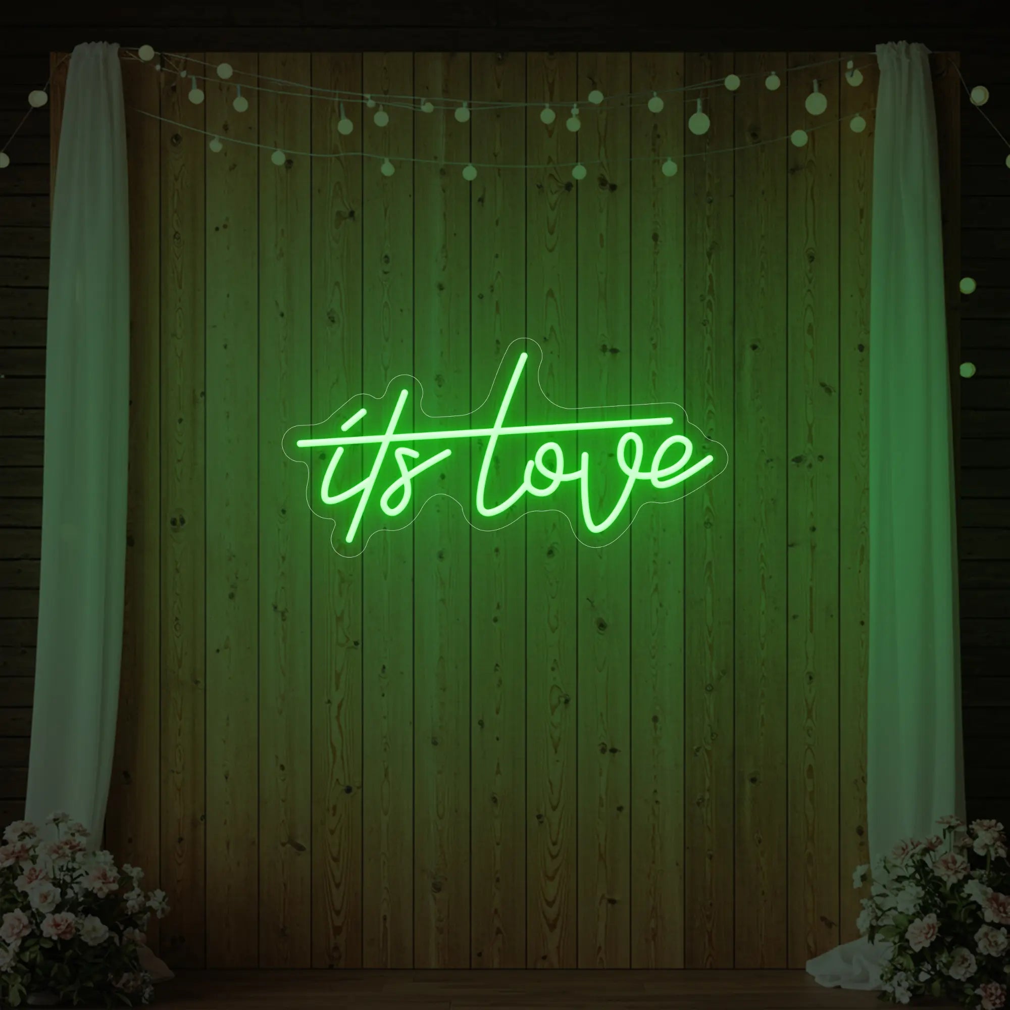 Photo of the 'It’s Love' neon sign glowing in green against a styled interior wall.
