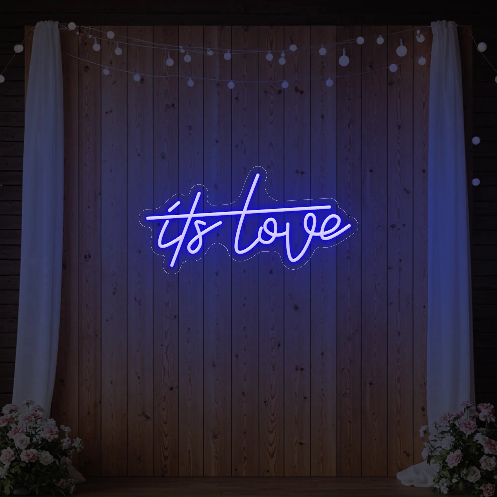 Photo of the 'It’s Love' neon sign glowing in deep blue against a styled interior wall.