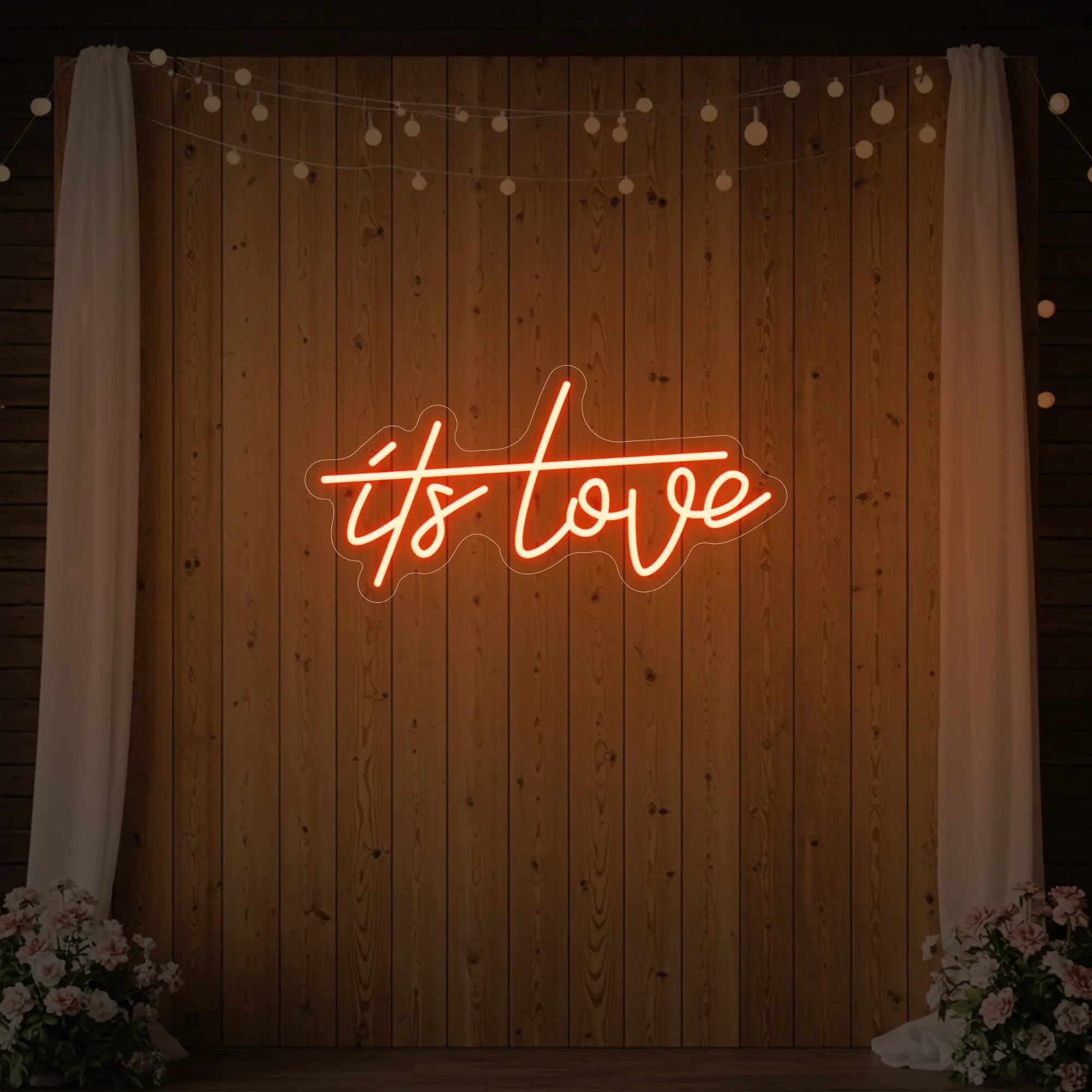 Photo of the 'It’s Love' neon sign glowing in golden yellow against a styled interior wall.