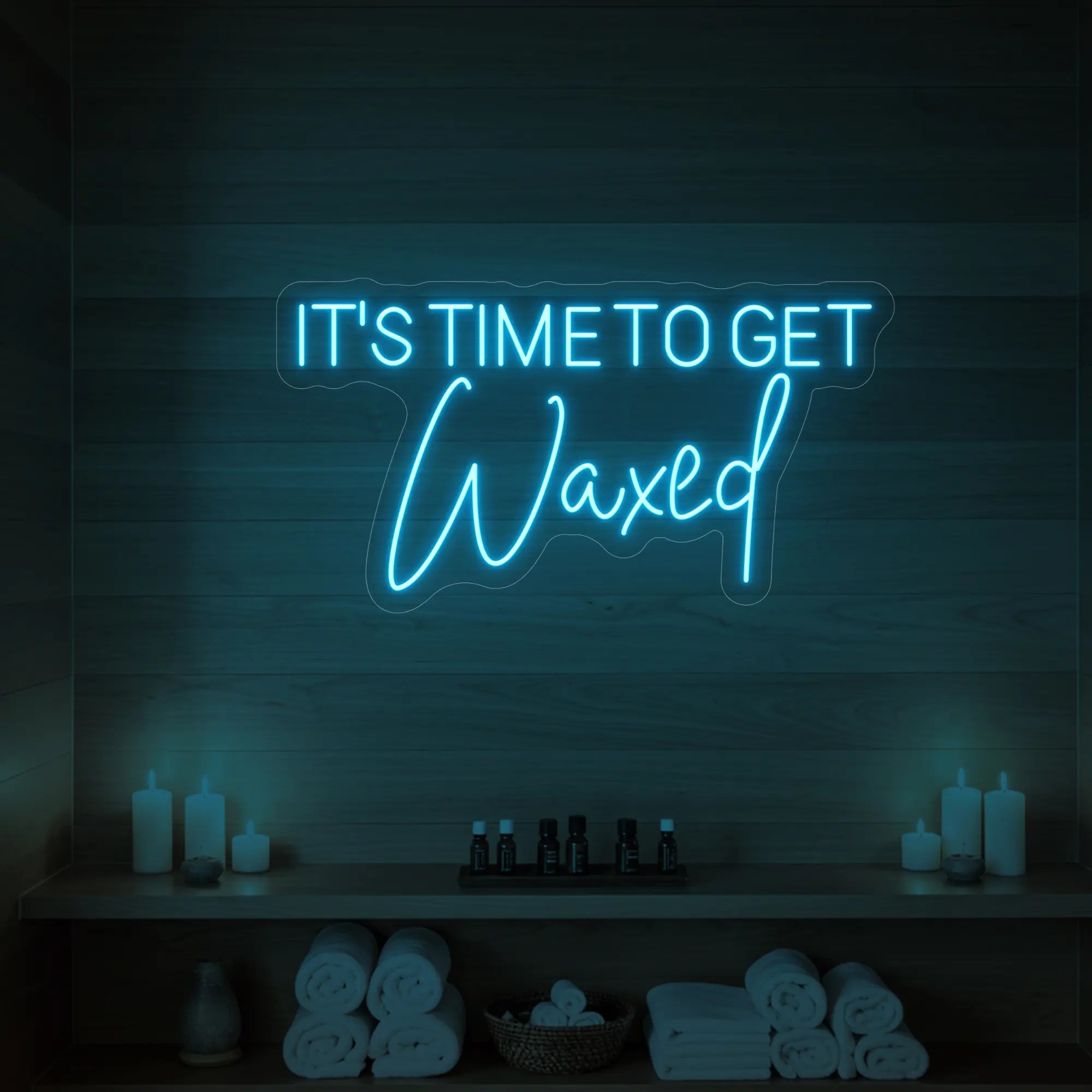Photo of the 'IT’S TIME TO GET Waxed' neon sign glowing in ice blue against a styled interior wall.