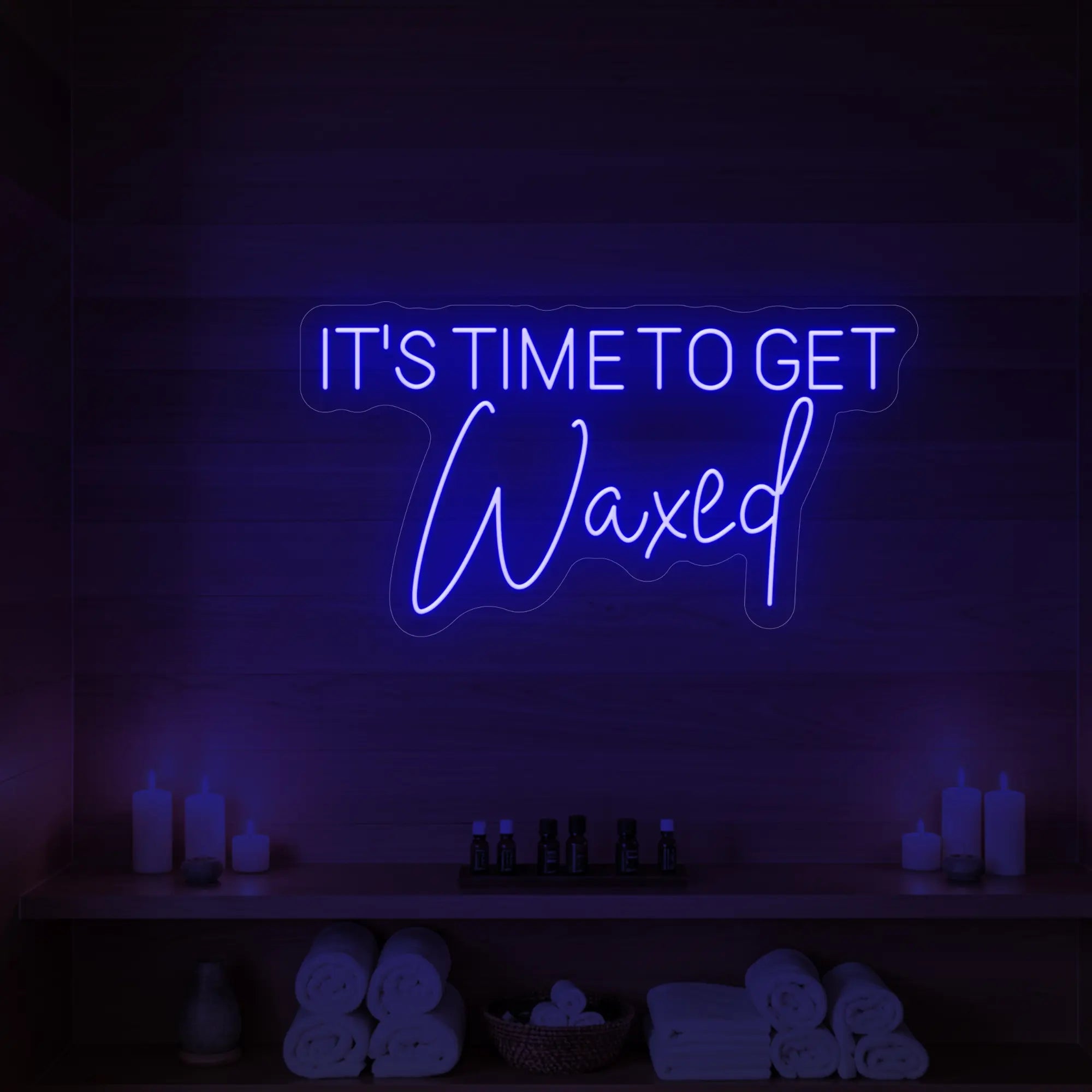 Photo of the 'IT’S TIME TO GET Waxed' neon sign glowing in deep blue against a styled interior wall.