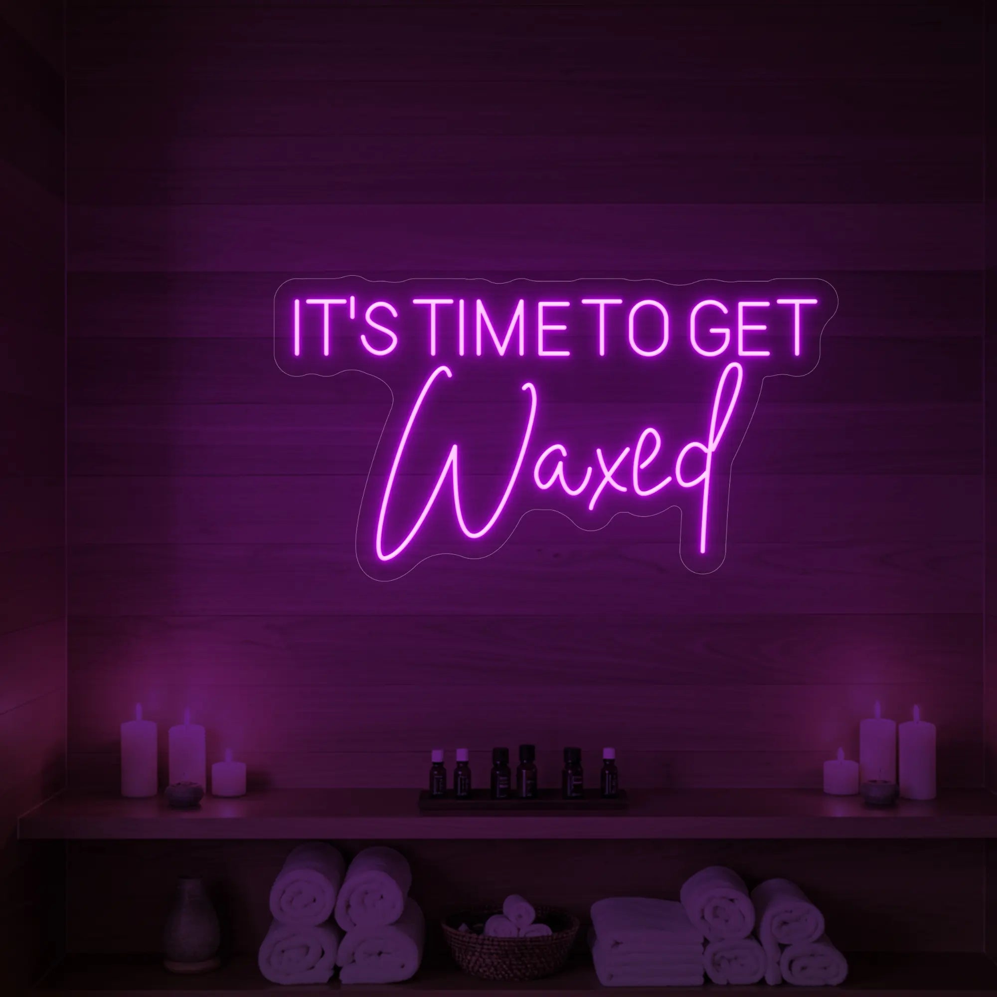 Photo of the 'IT’S TIME TO GET Waxed' neon sign glowing in deep pink against a styled interior wall.