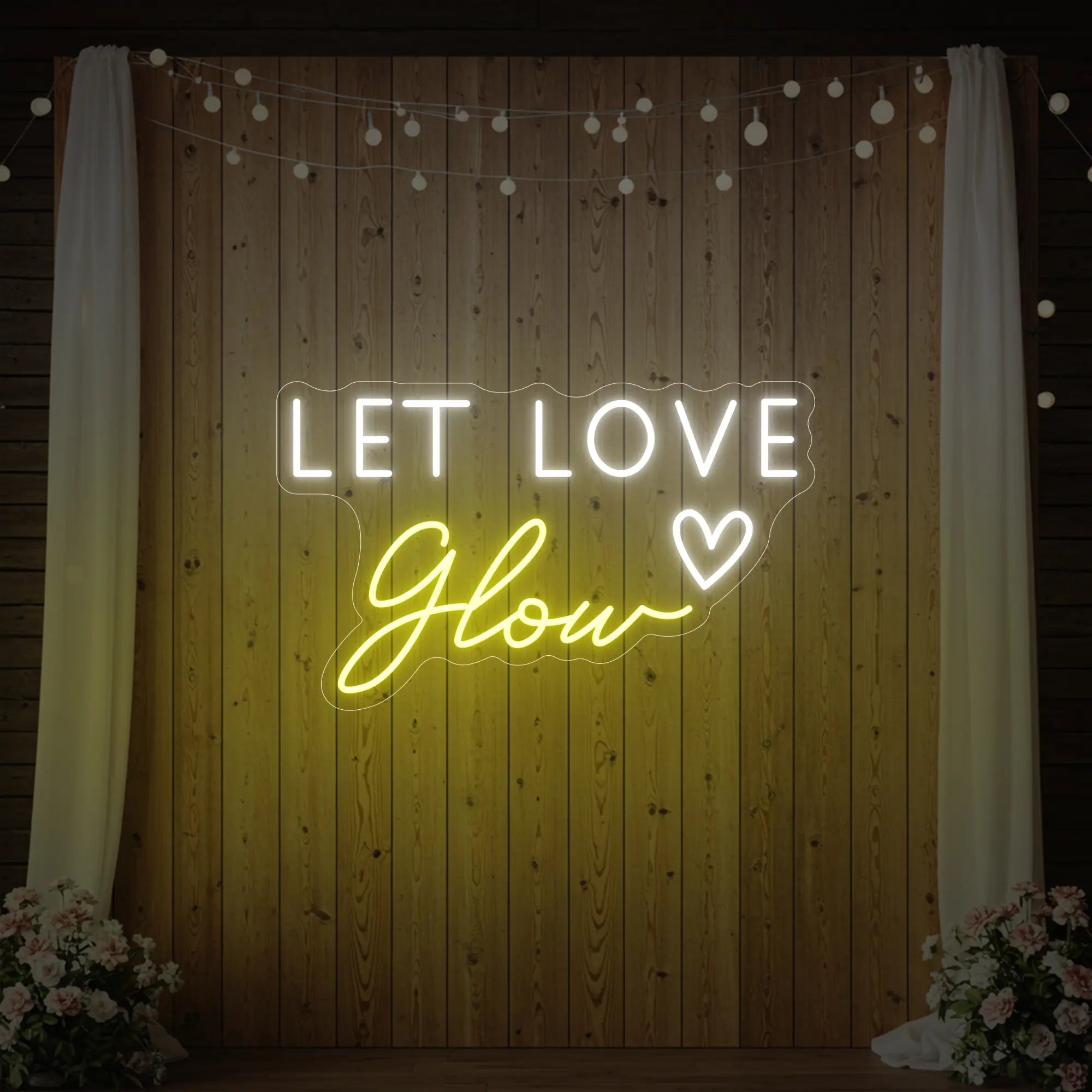 Photo of the 'Let Love Glow' neon sign glowing in lemon yellow against a styled interior wall.