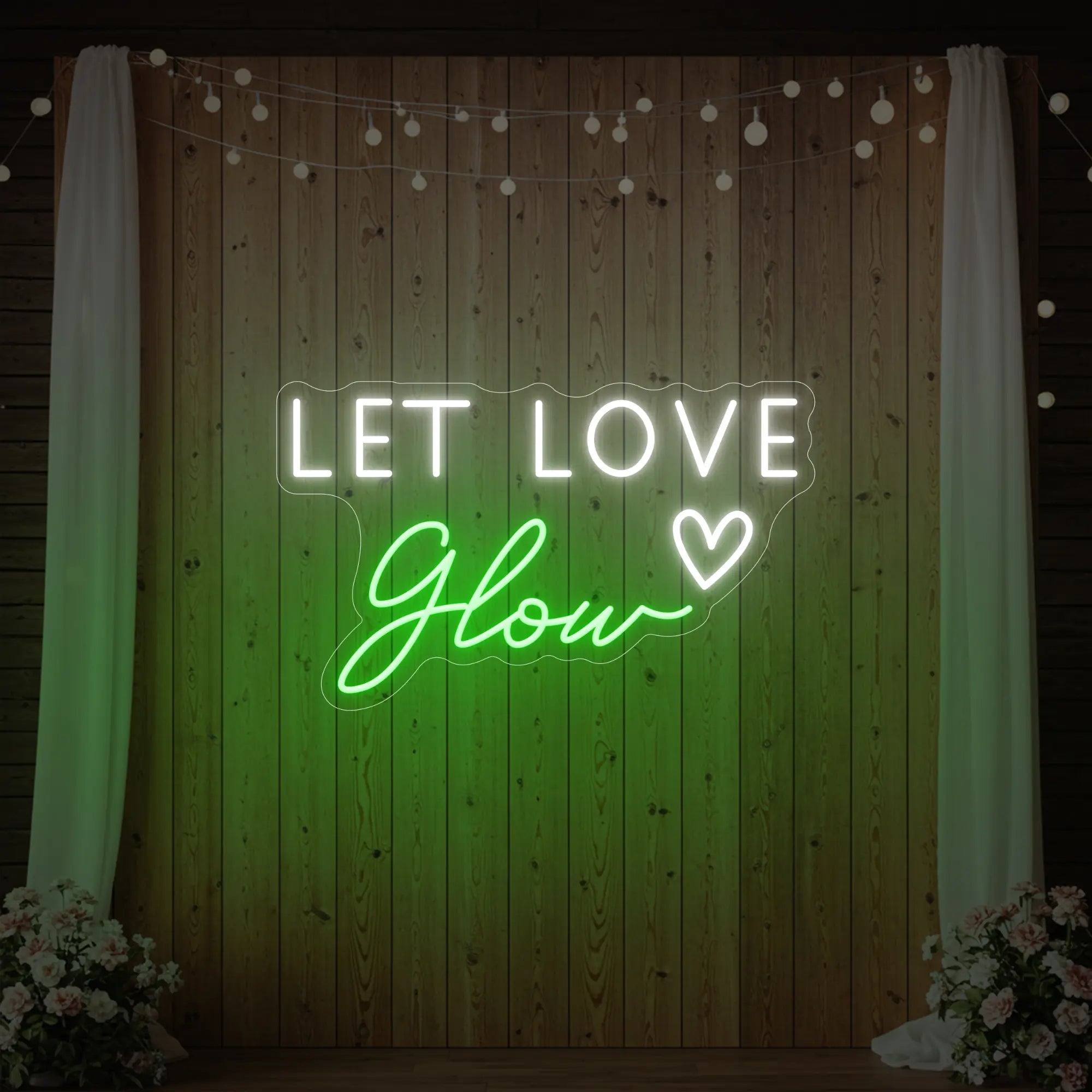 Photo of the 'Let Love Glow' neon sign glowing in green against a styled interior wall.
