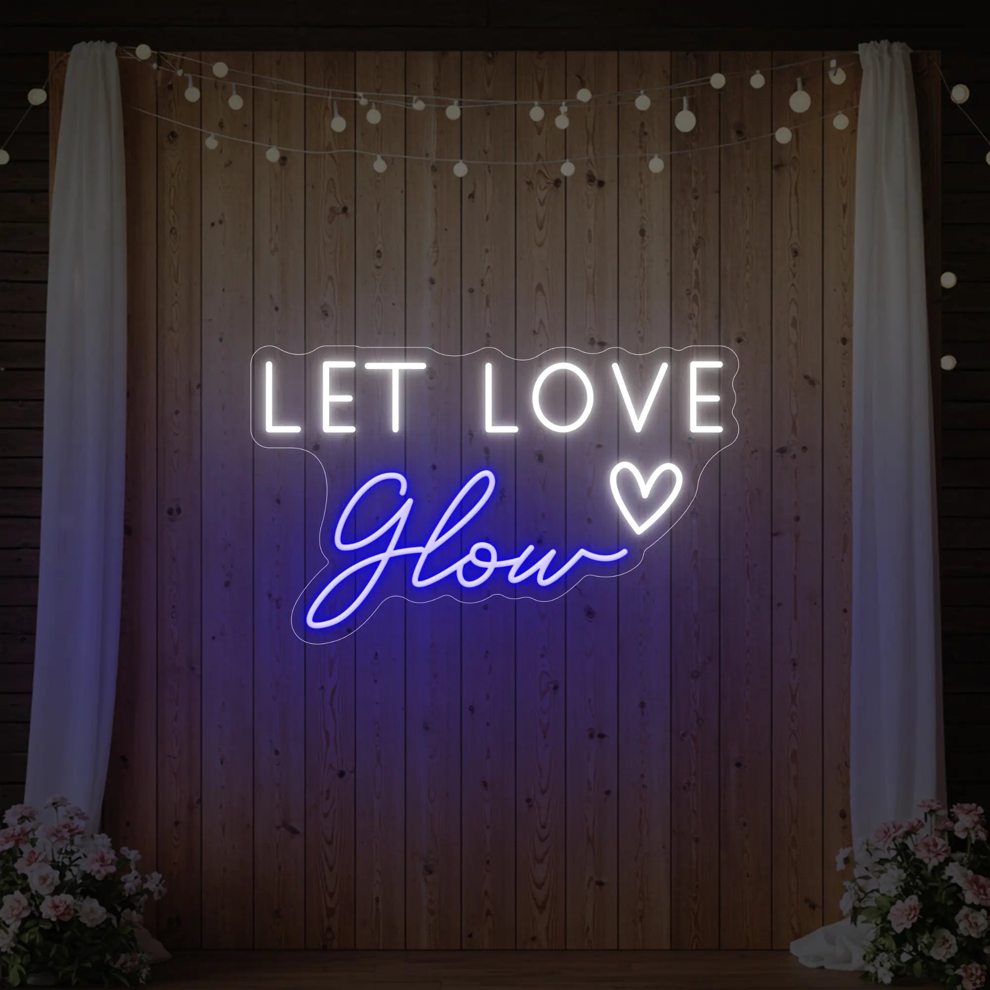 Photo of the 'Let Love Glow' neon sign glowing in deep blue against a styled interior wall.