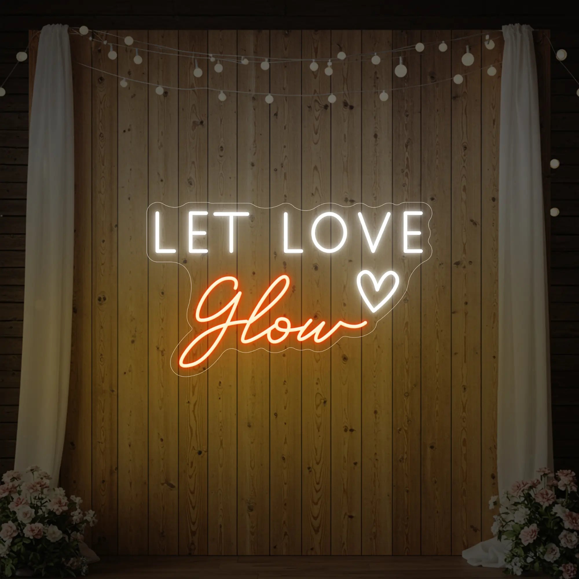 Photo of the 'Let Love Glow' neon sign glowing in golden yellow against a styled interior wall.