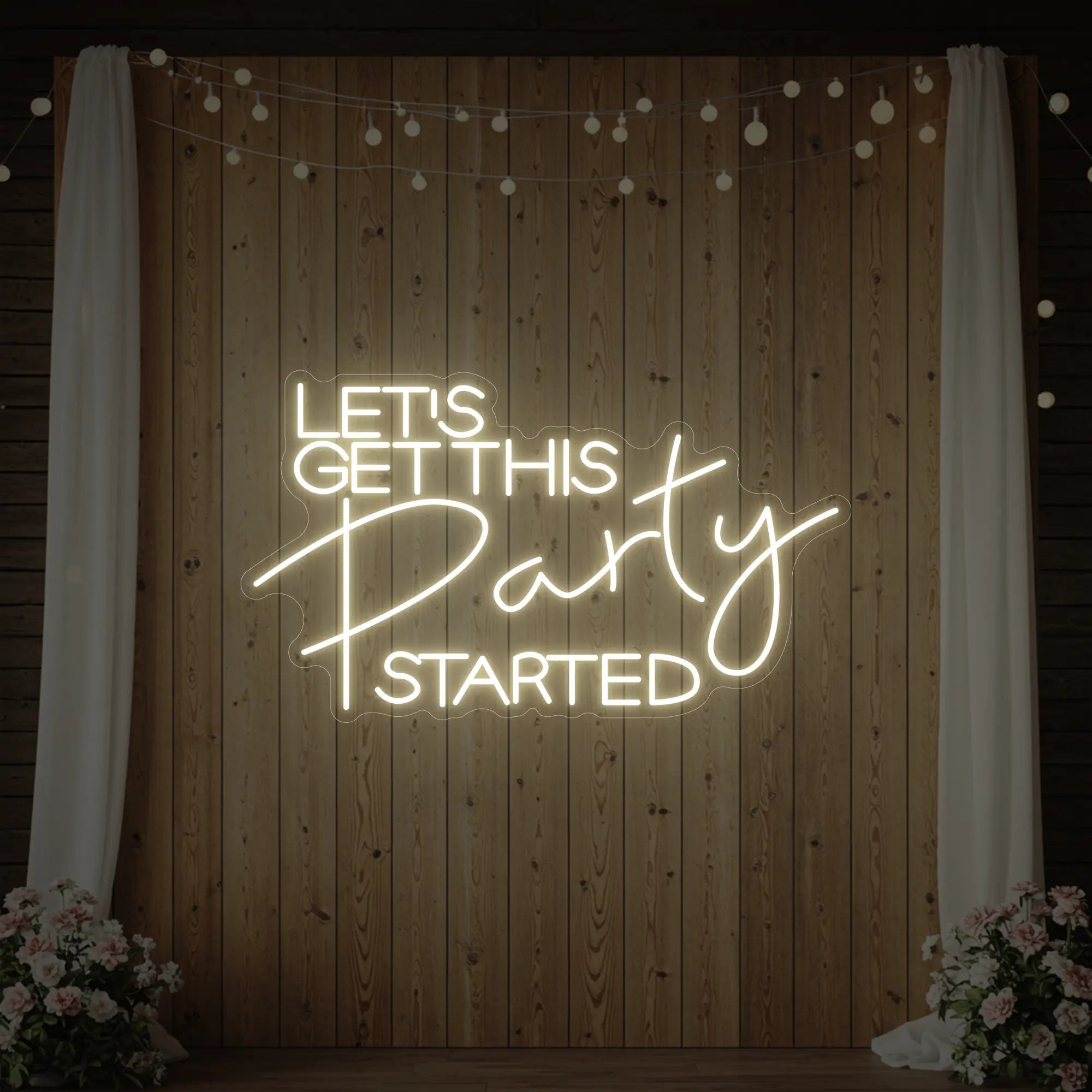 Photo of the 'Let’s Get This Party Started' neon sign glowing in warm white against a styled interior wall.