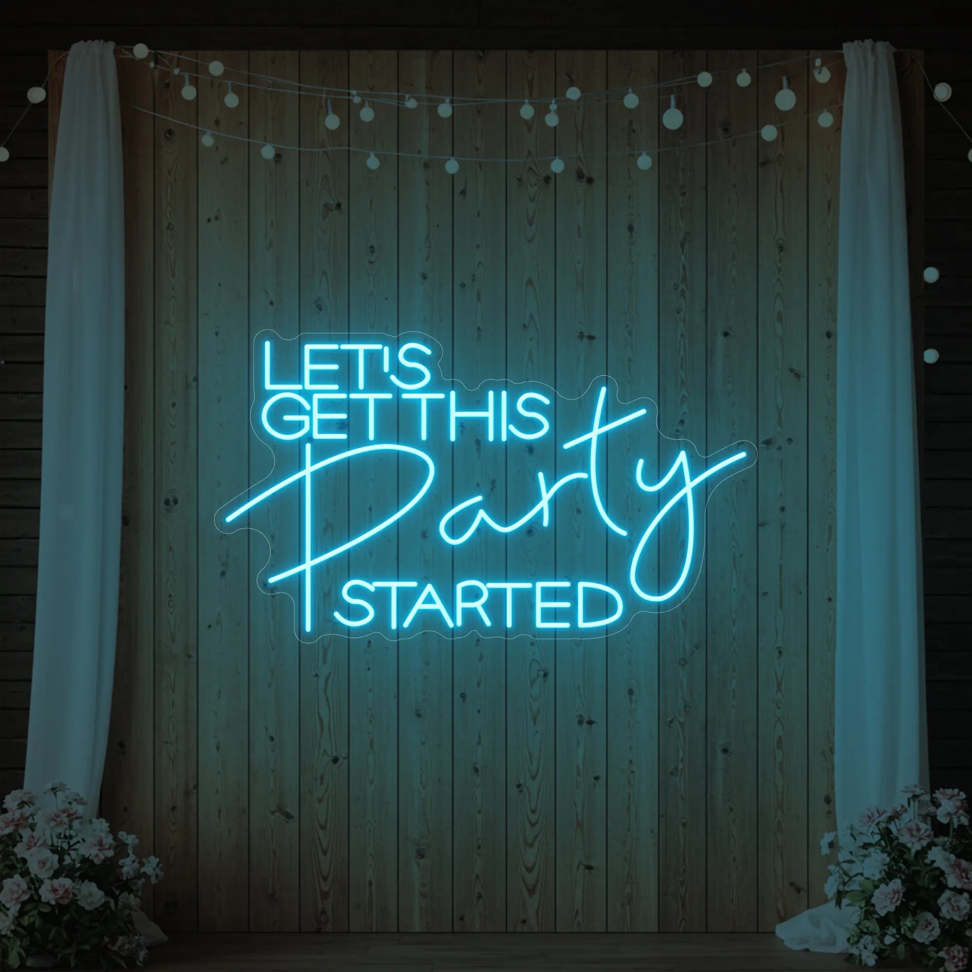 Photo of the 'Let’s Get This Party Started' neon sign glowing in ice blue against a styled interior wall.