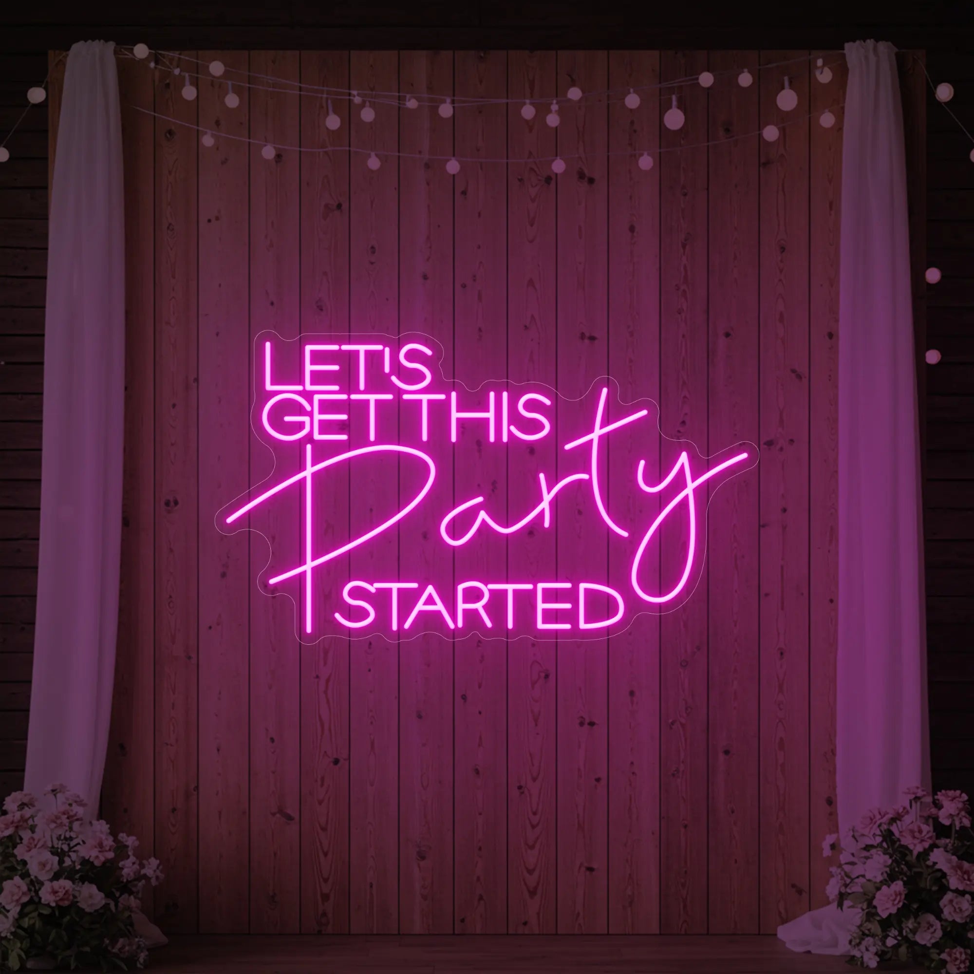 Photo of the 'Let’s Get This Party Started' neon sign glowing in light pink against a styled interior wall.
