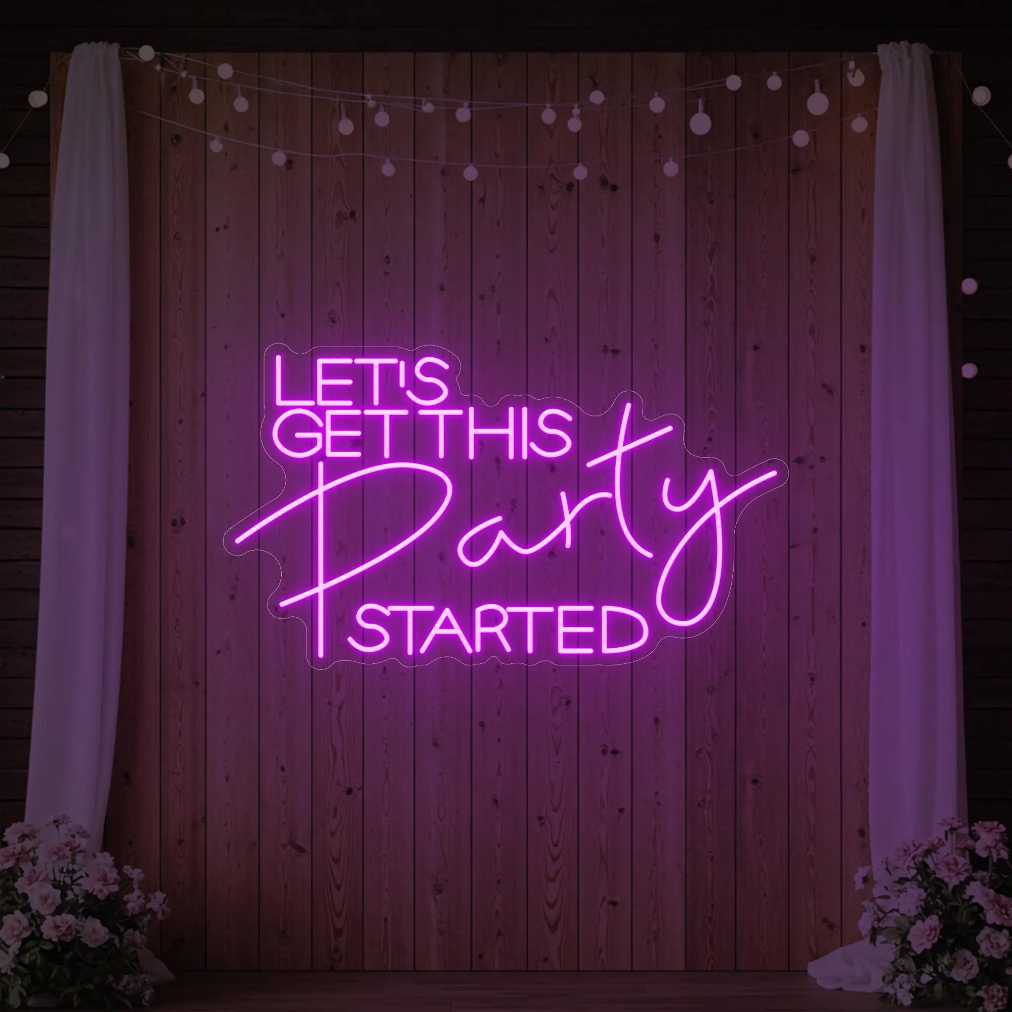 Photo of the 'Let’s Get This Party Started' neon sign glowing in deep pink against a styled interior wall.
