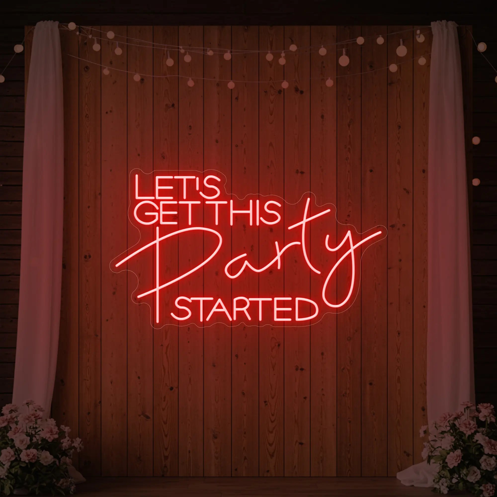 Photo of the 'Let’s Get This Party Started' neon sign glowing in red against a styled interior wall.
