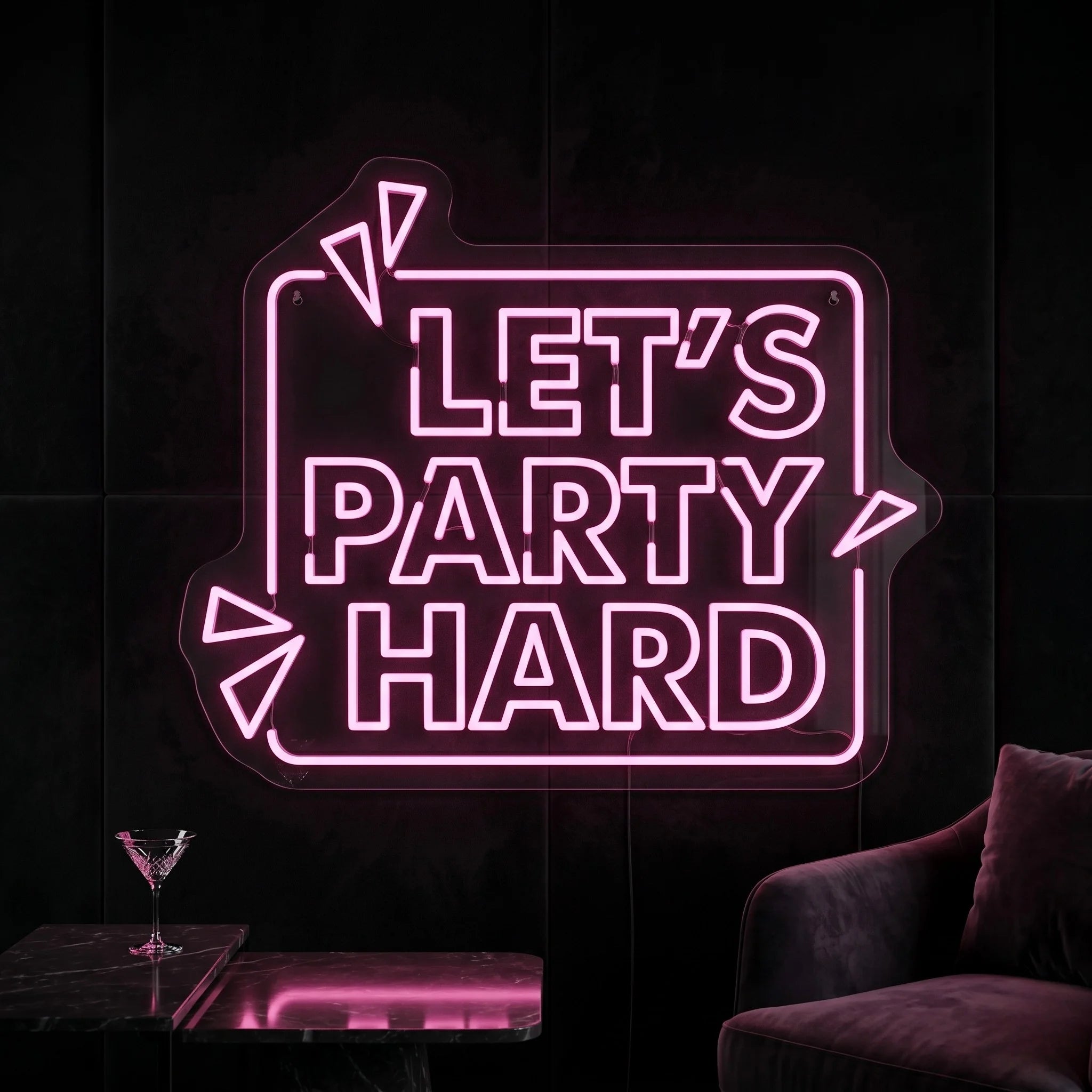 Photo of the 'Let's Party Hard' neon sign glowing in peach pink against a styled interior wall.
