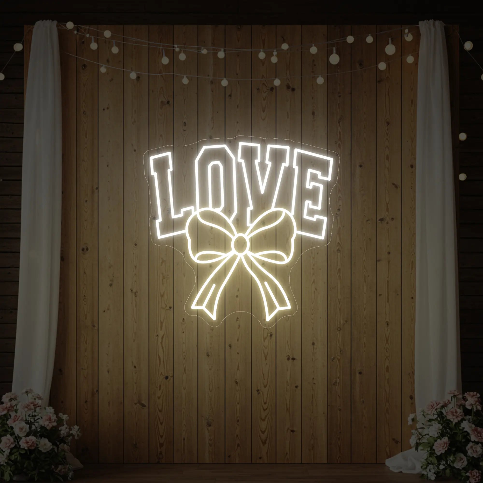 Photo of the 'Love and Ribbon' neon sign glowing in warm white against a styled interior wall.