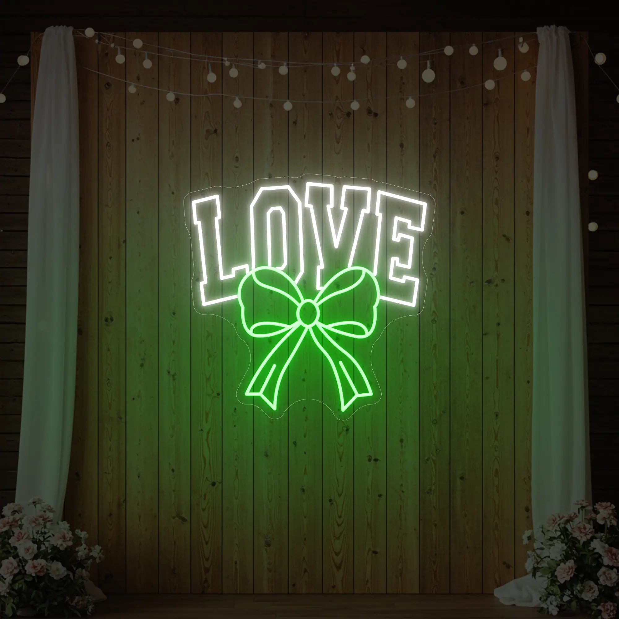 Photo of the 'Love and Ribbon' neon sign glowing in green against a styled interior wall.