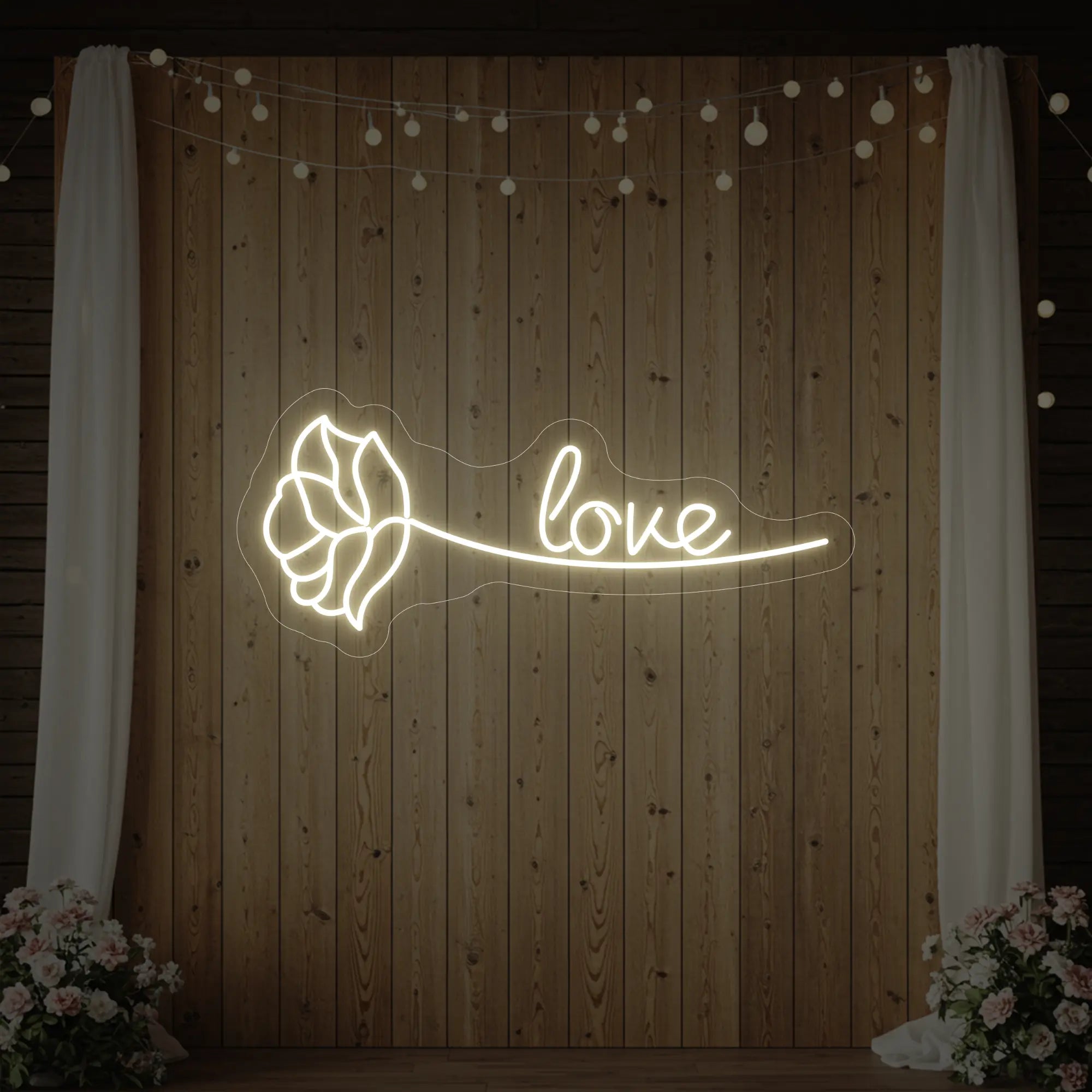 Photo of the 'Just Love Rose' neon sign glowing in warm white against a styled interior wall.