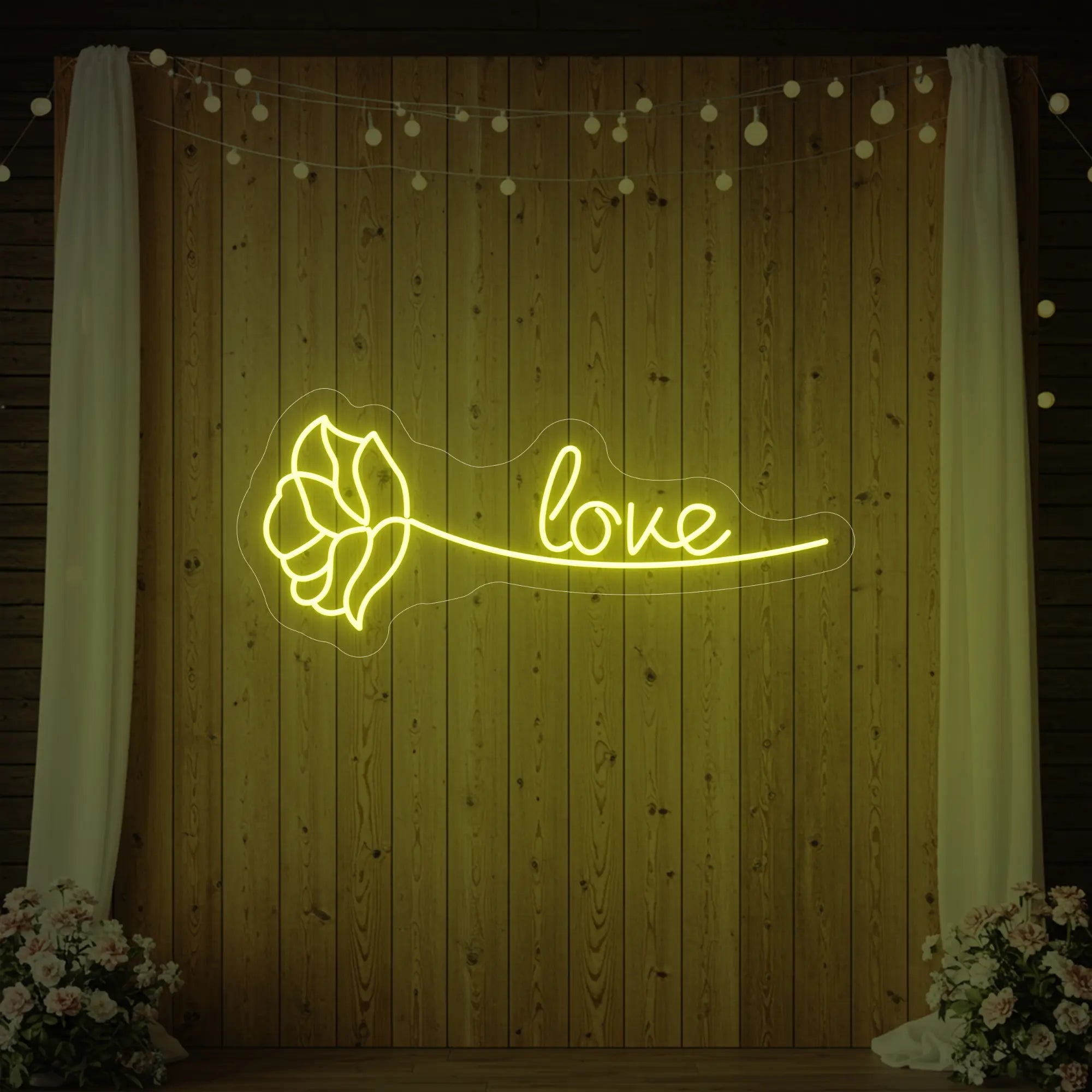 Photo of the 'Just Love Rose' neon sign glowing in lemon yellow against a styled interior wall.