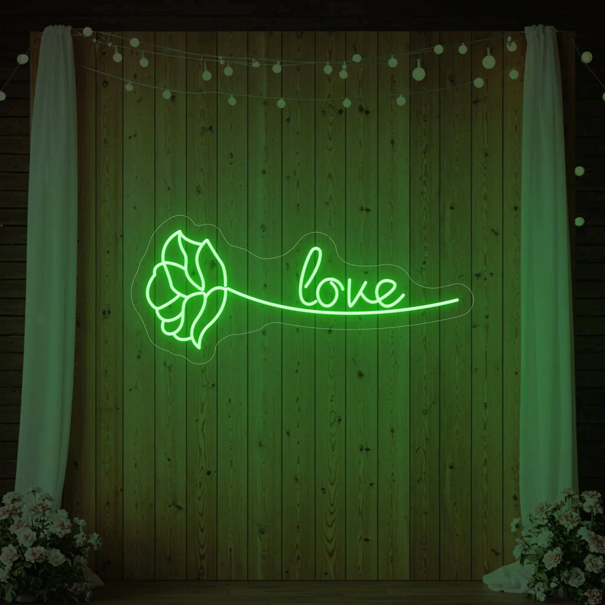 Photo of the 'Just Love Rose' neon sign glowing in green against a styled interior wall.