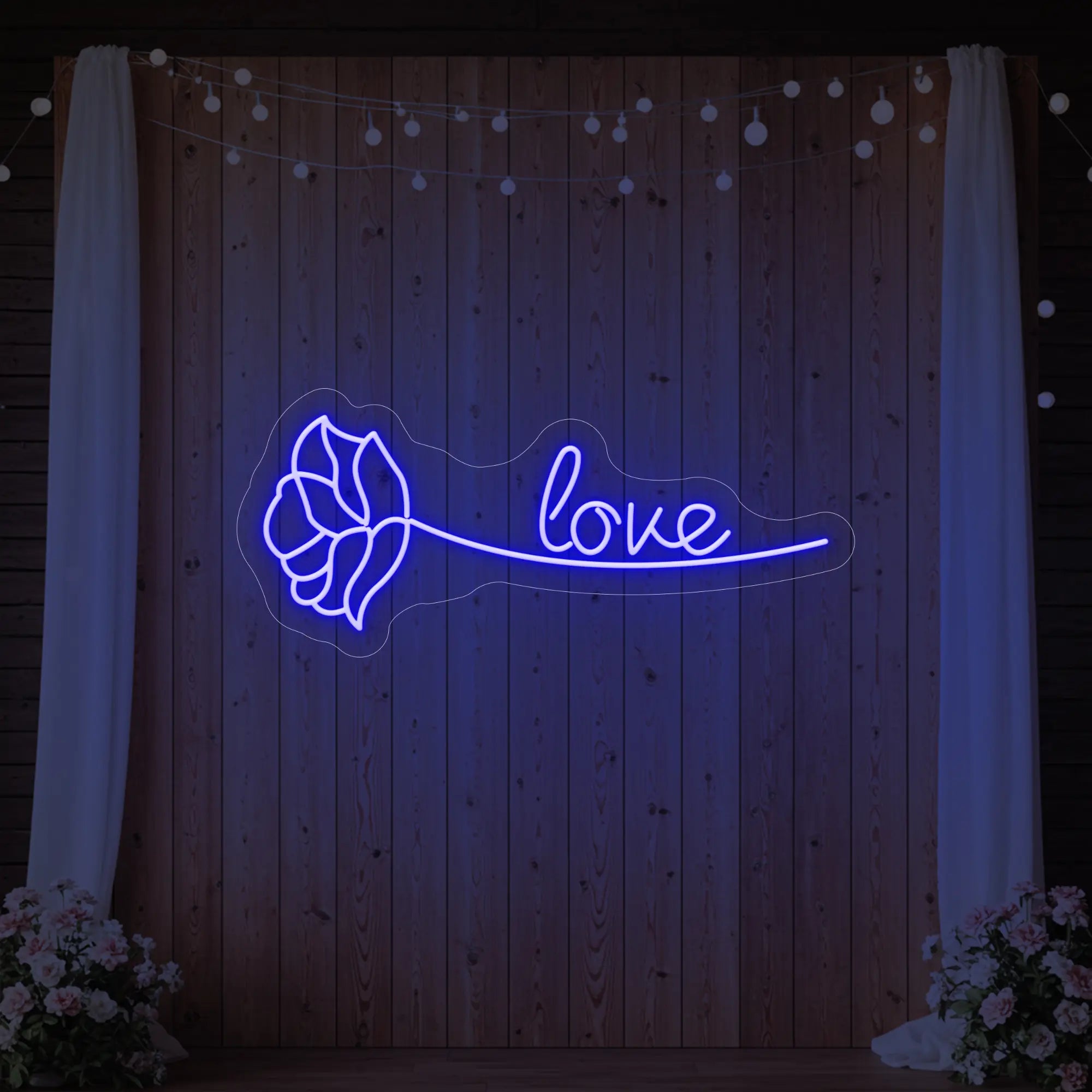 Photo of the 'Just Love Rose' neon sign glowing in deep blue against a styled interior wall.