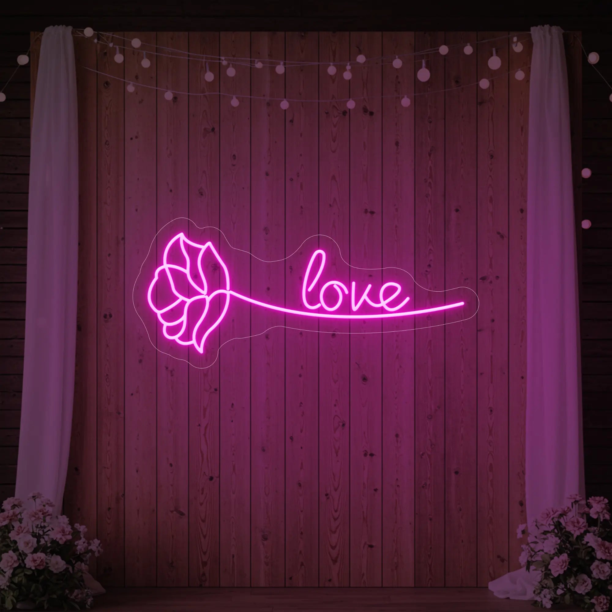 Photo of the 'Just Love Rose' neon sign glowing in light pink against a styled interior wall.