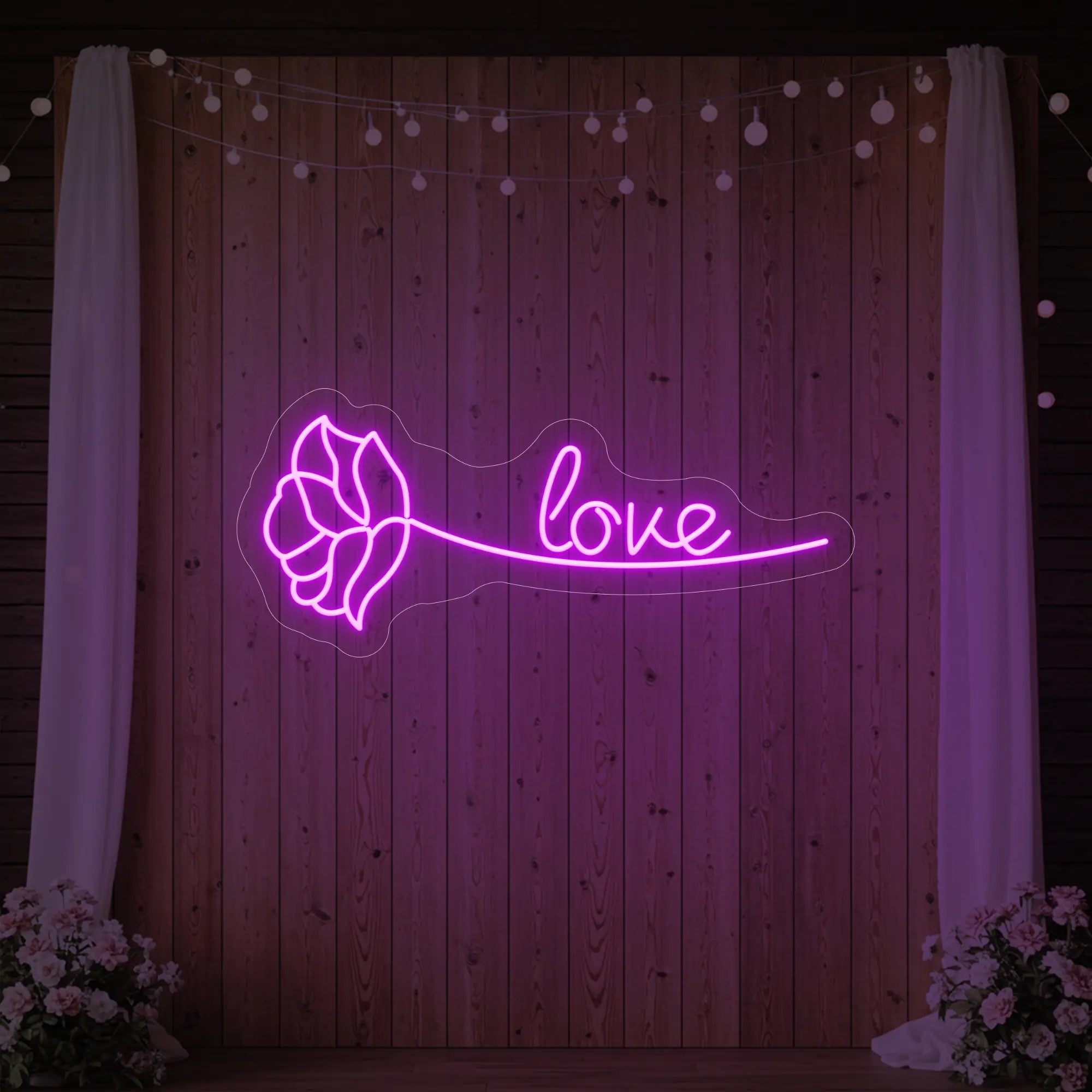 Photo of the 'Just Love Rose' neon sign glowing in deep pink against a styled interior wall.