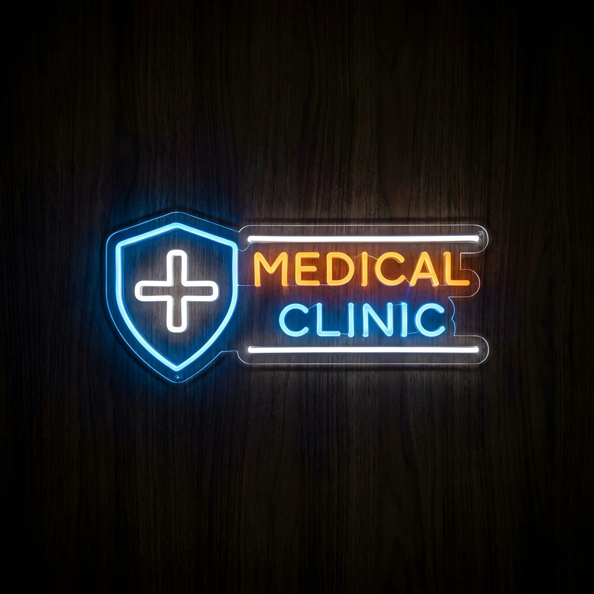 Medical Clinic Shield LED Neon Sign featuring a blue shield with a white medical cross, orange MEDICAL lettering, and blue CLINIC text on clear acrylic backing against a dark wooden wall.