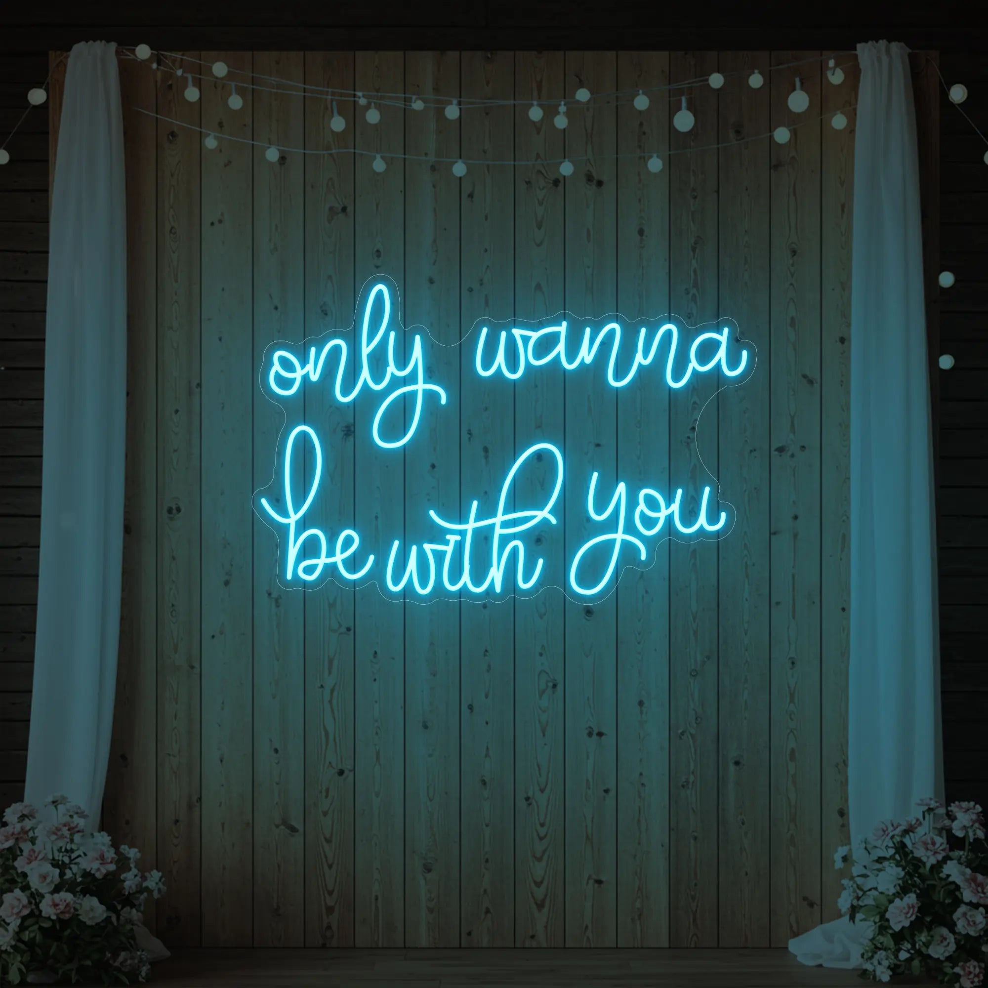 Photo of the 'Only Wanna Be With You' neon sign glowing in ice blue against a styled interior wall.