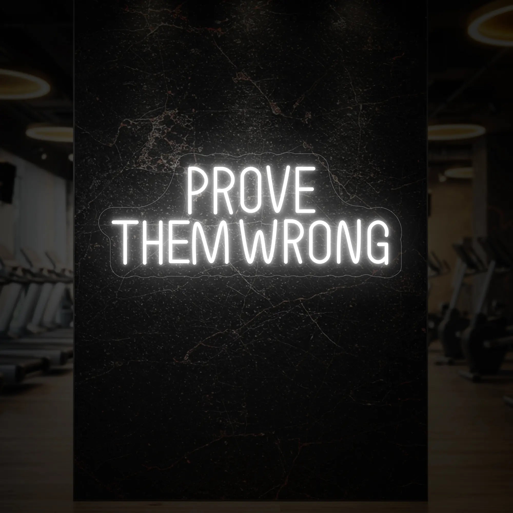'PROVE THEM WRONG' neon sign glowing in cool white against a styled interior wall.