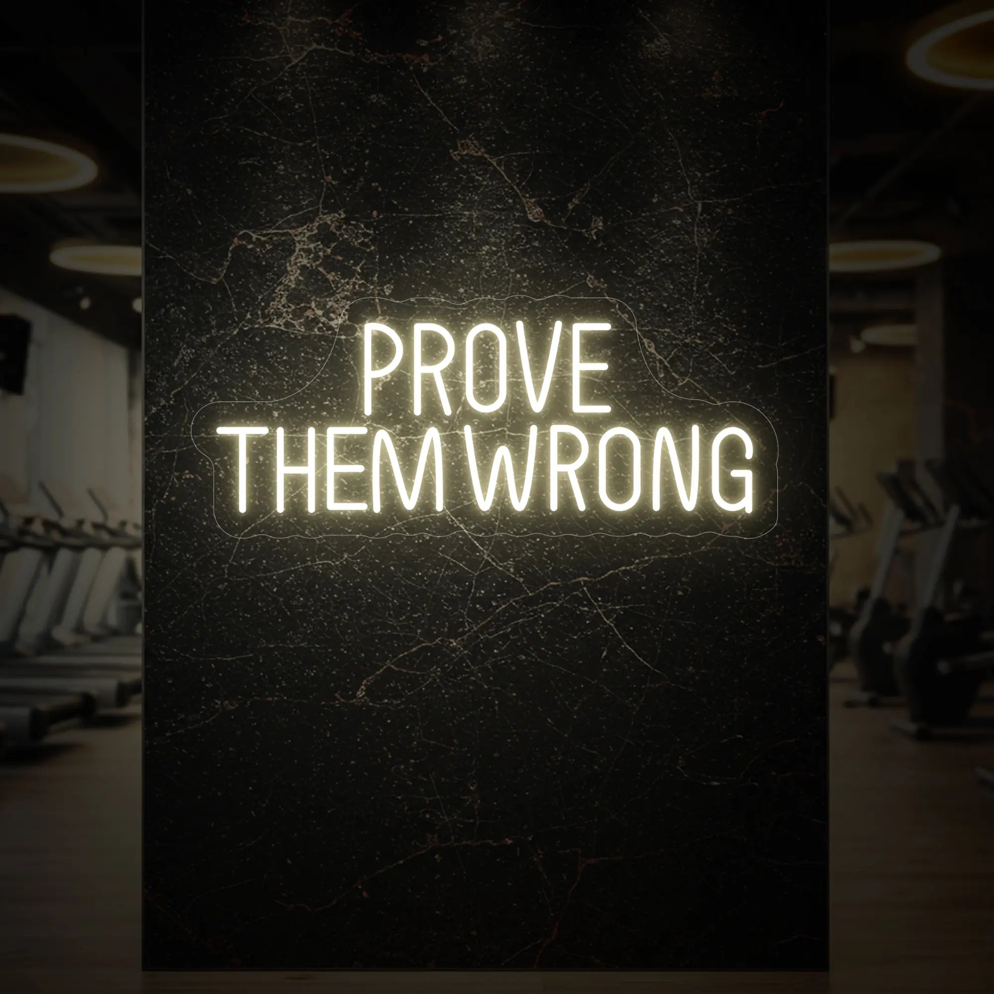 'PROVE THEM WRONG' neon sign glowing in warm white against a styled interior wall.