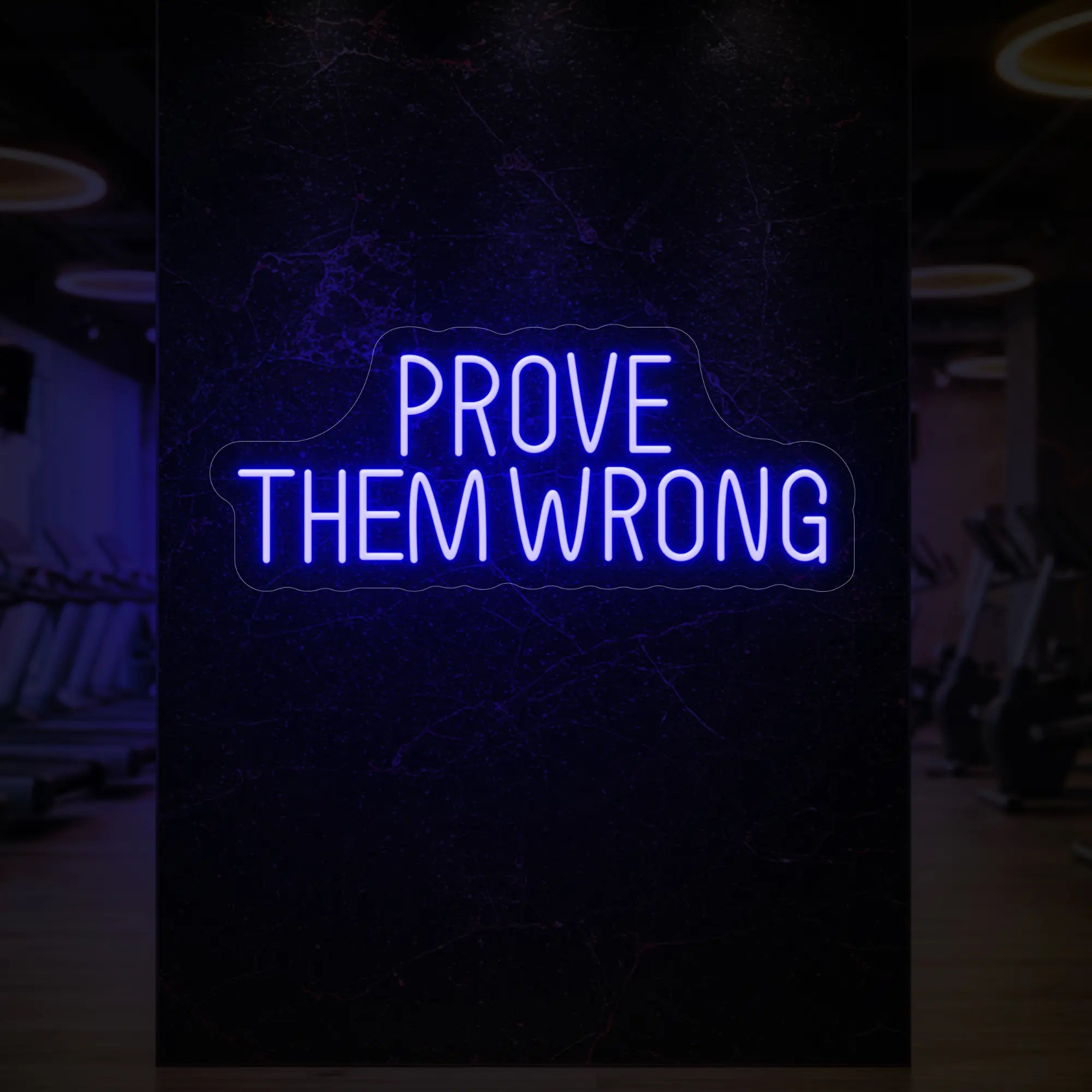 'PROVE THEM WRONG' neon sign glowing in deep blue against a styled interior wall.