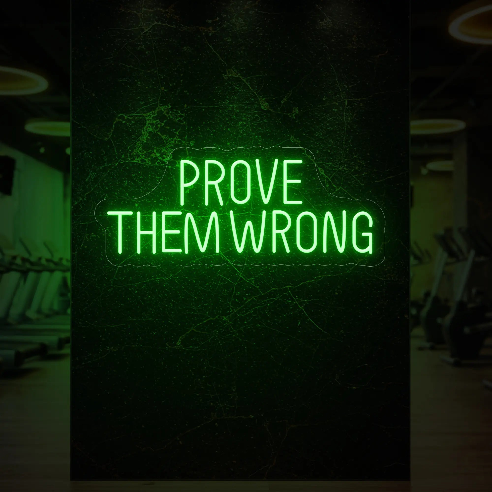 'PROVE THEM WRONG' neon sign glowing in green against a styled interior wall.