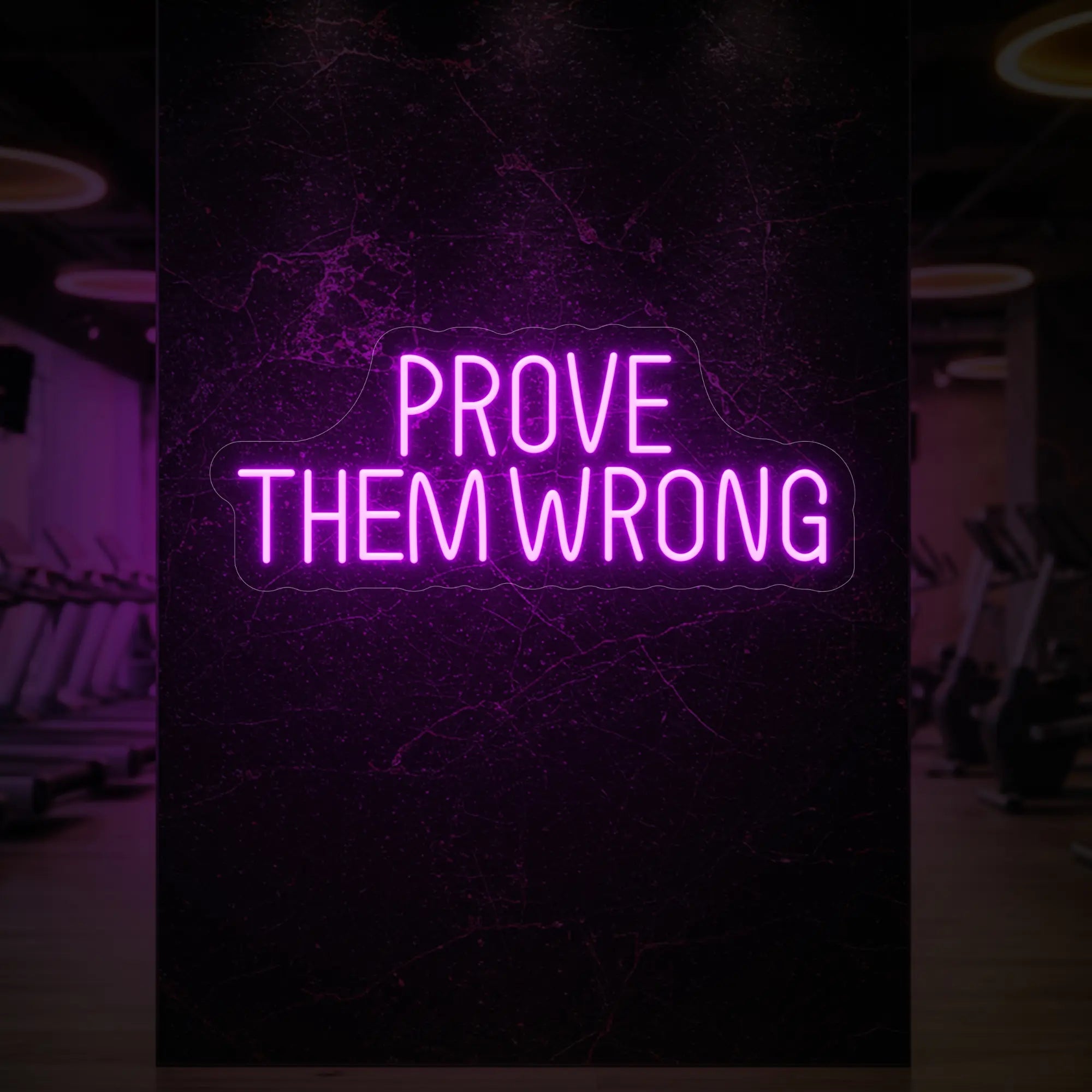 'PROVE THEM WRONG' neon sign glowing in deep pink against a styled interior wall.