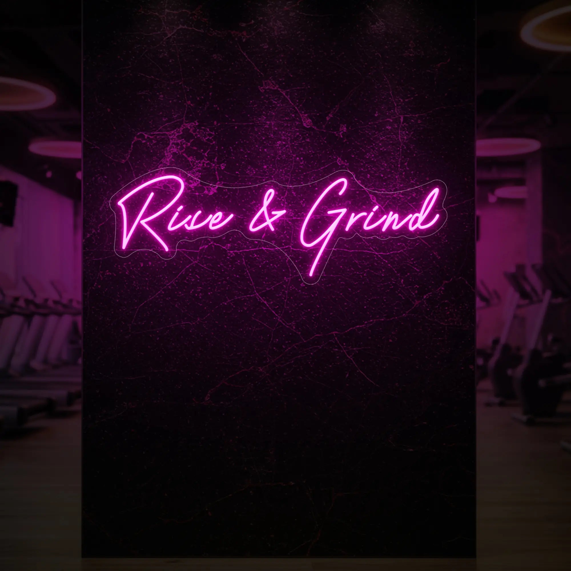 'Rise & Grind' neon sign glowing in deep pink against a styled interior wall.