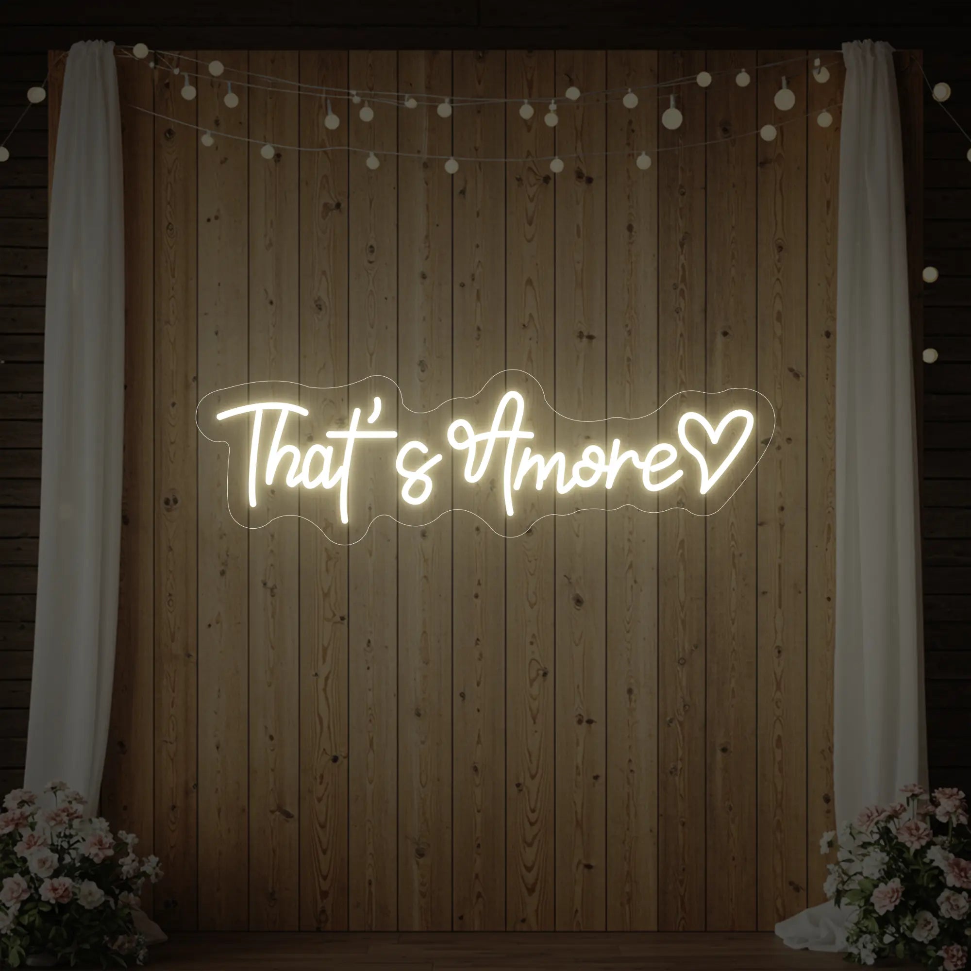 Photo of the 'That's Amore with Heart' neon sign glowing in warm white against a styled interior wall.