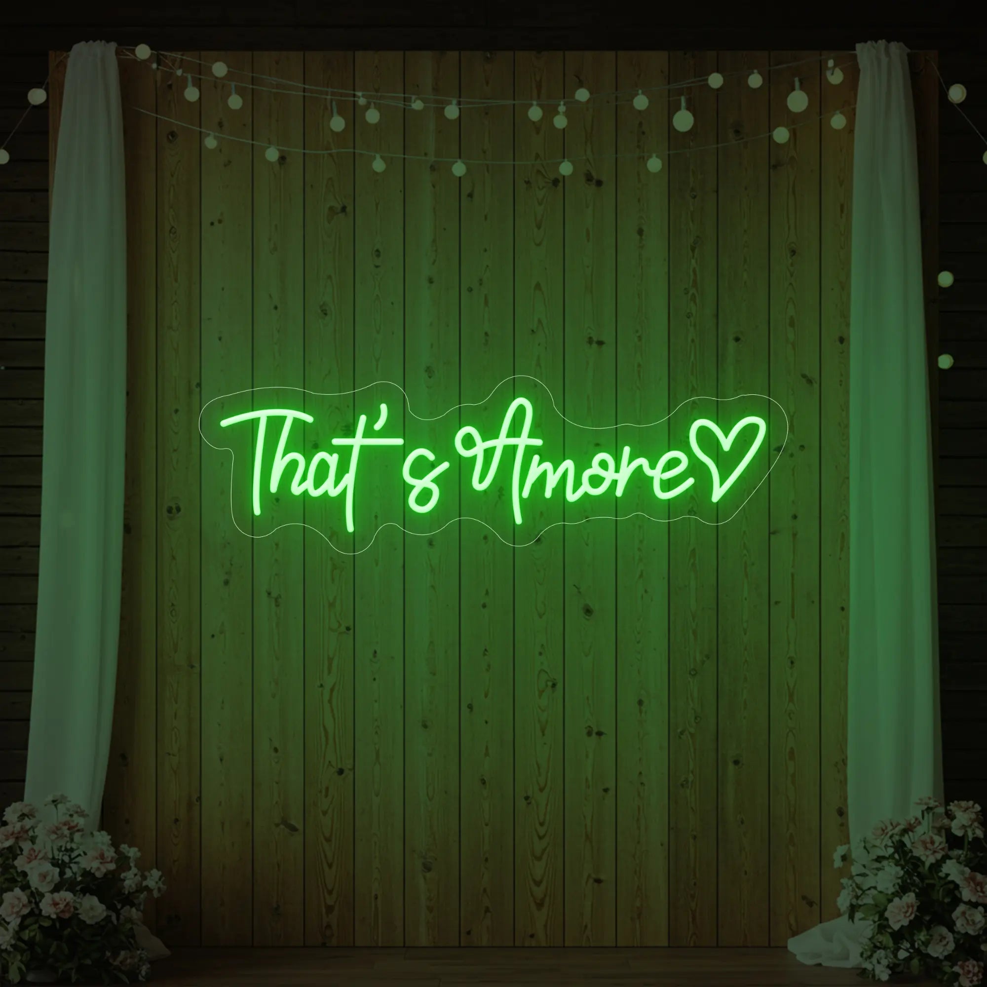 Photo of the 'That's Amore with Heart' neon sign glowing in green against a styled interior wall.