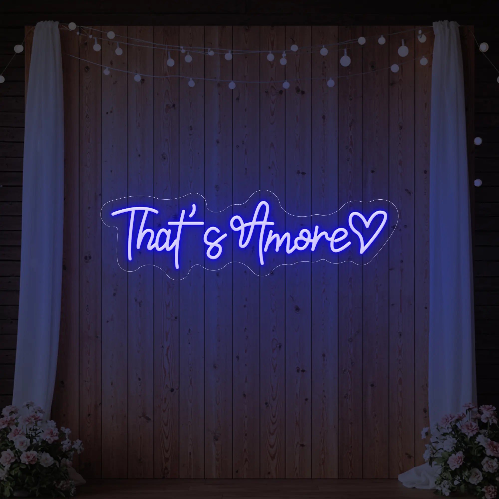 Photo of the 'That's Amore with Heart' neon sign glowing in deep blue against a styled interior wall.