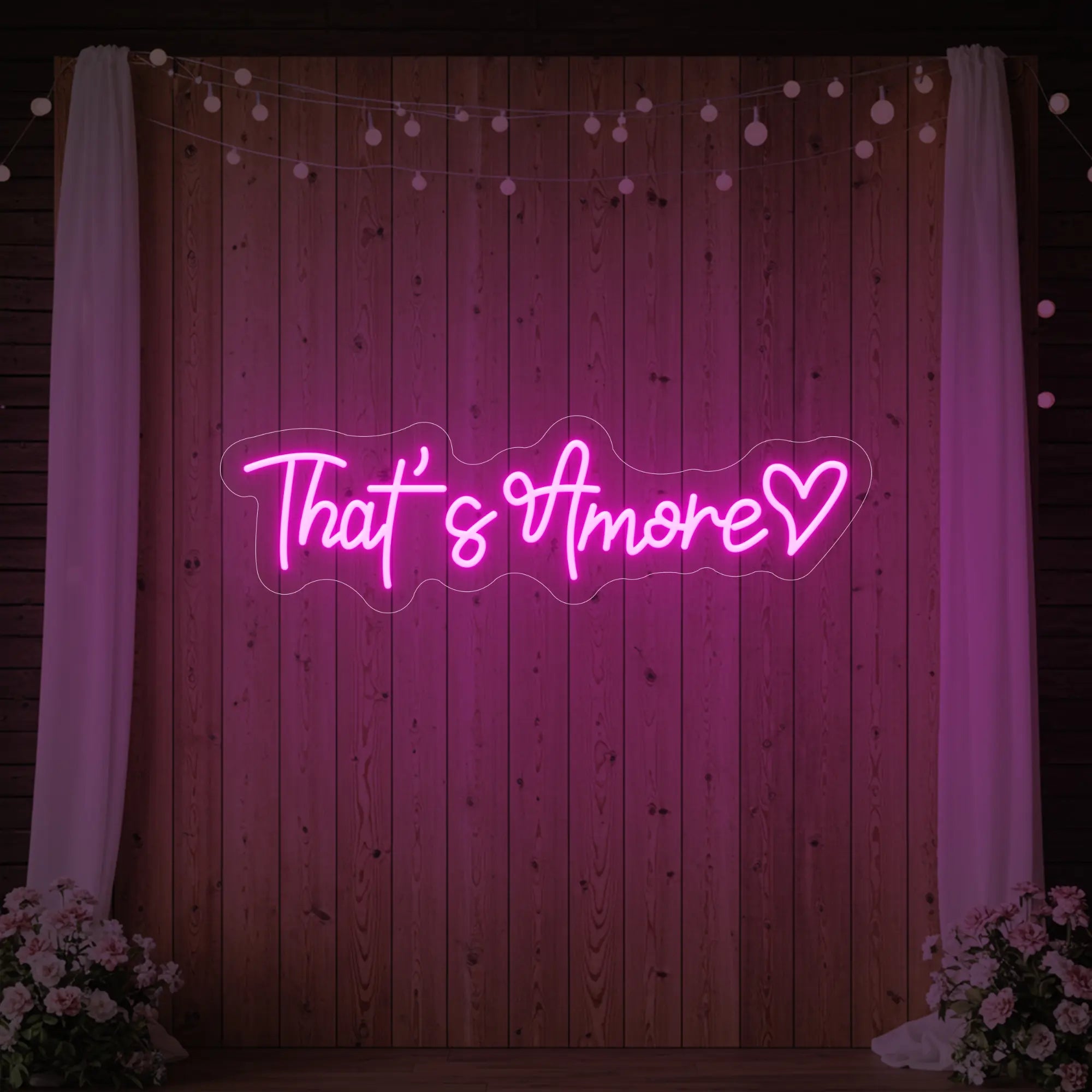 Photo of the 'That's Amore with Heart' neon sign glowing in light pink against a styled interior wall.