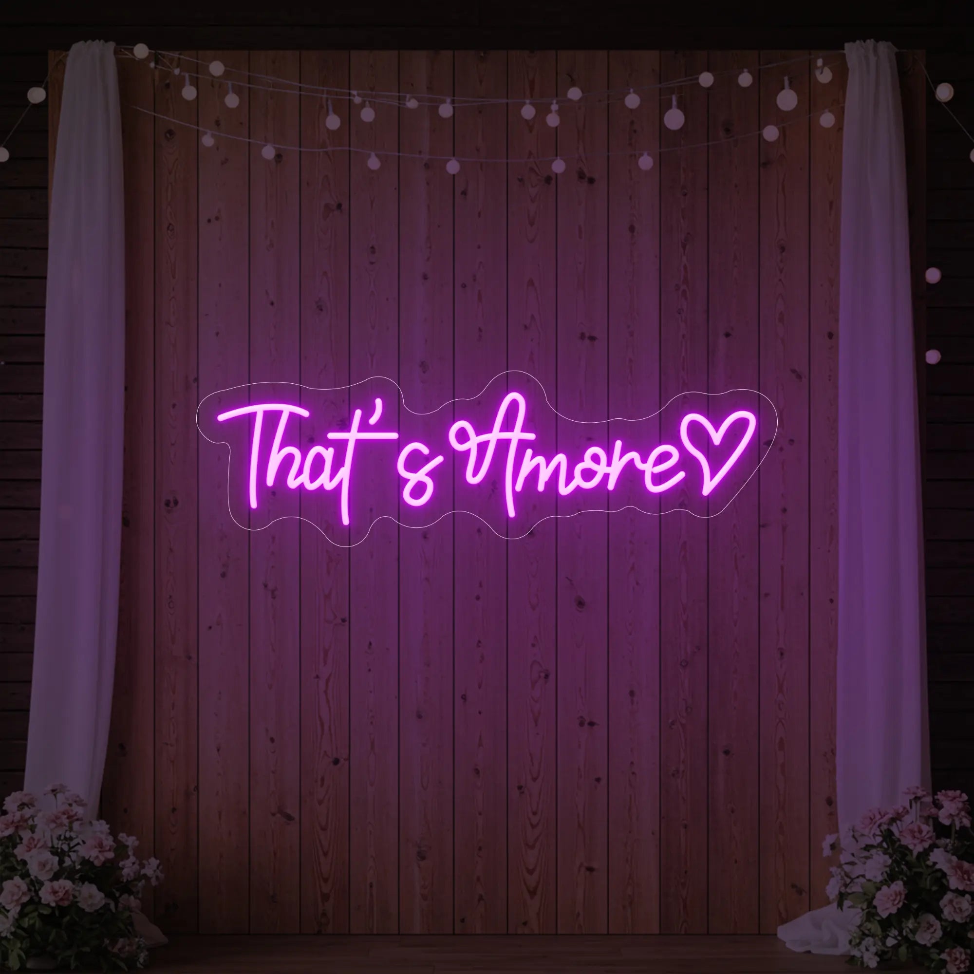 Photo of the 'That's Amore with Heart' neon sign glowing in deep pink against a styled interior wall.