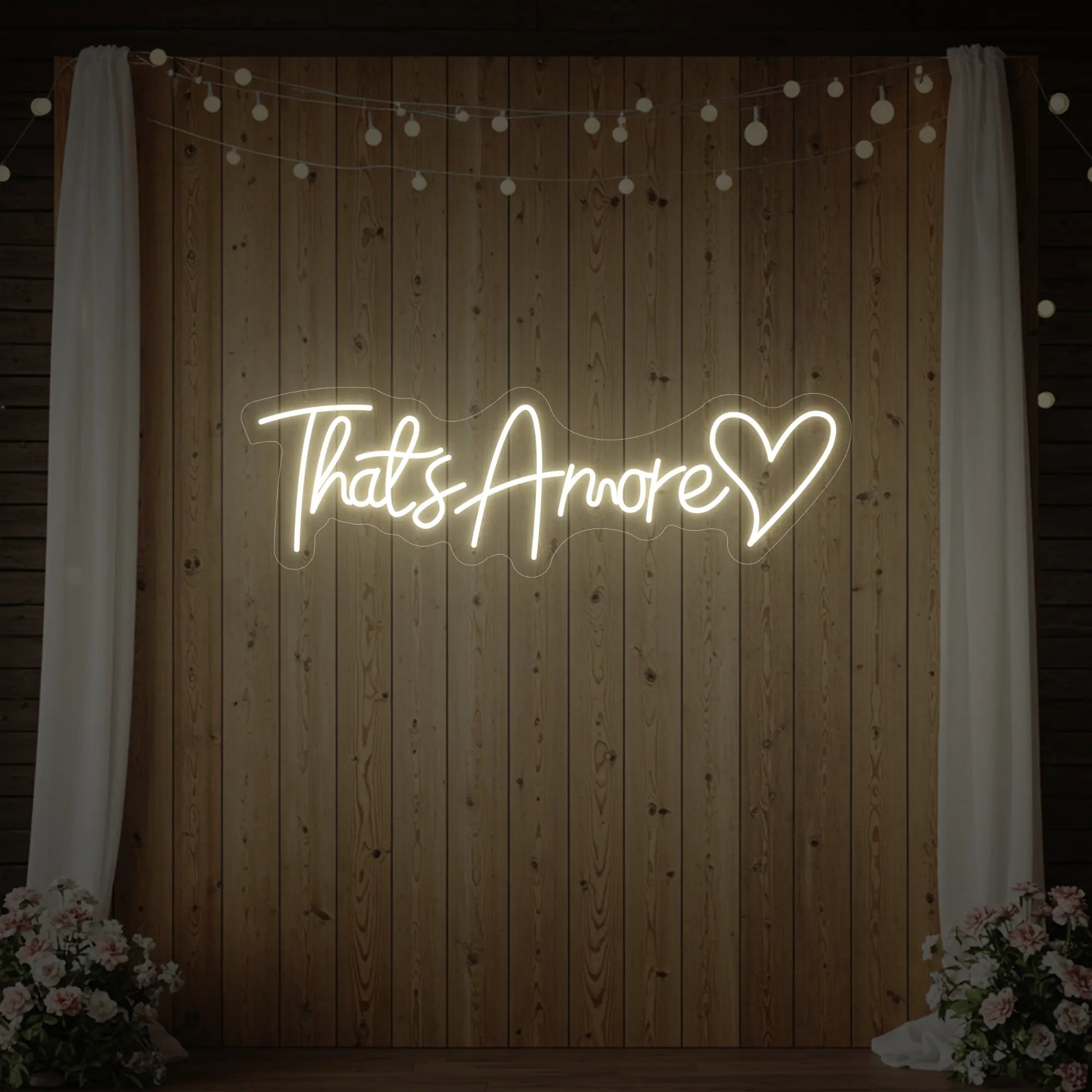 Photo of the 'That's Amore with Heart' neon sign glowing in warm white against a styled interior wall.