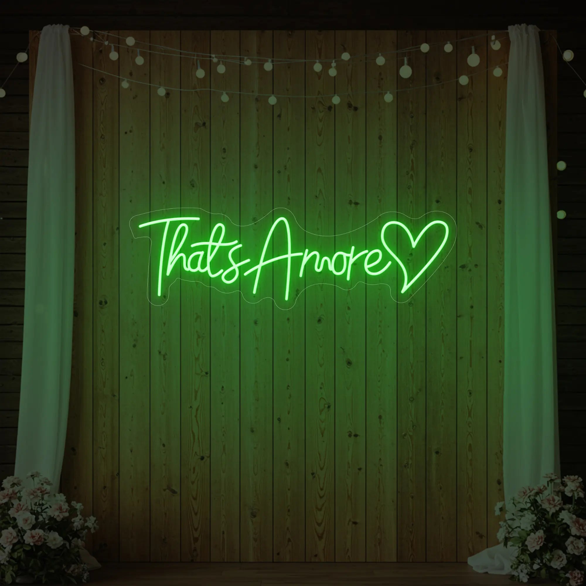 Photo of the 'That's Amore with Heart' neon sign glowing in green against a styled interior wall.